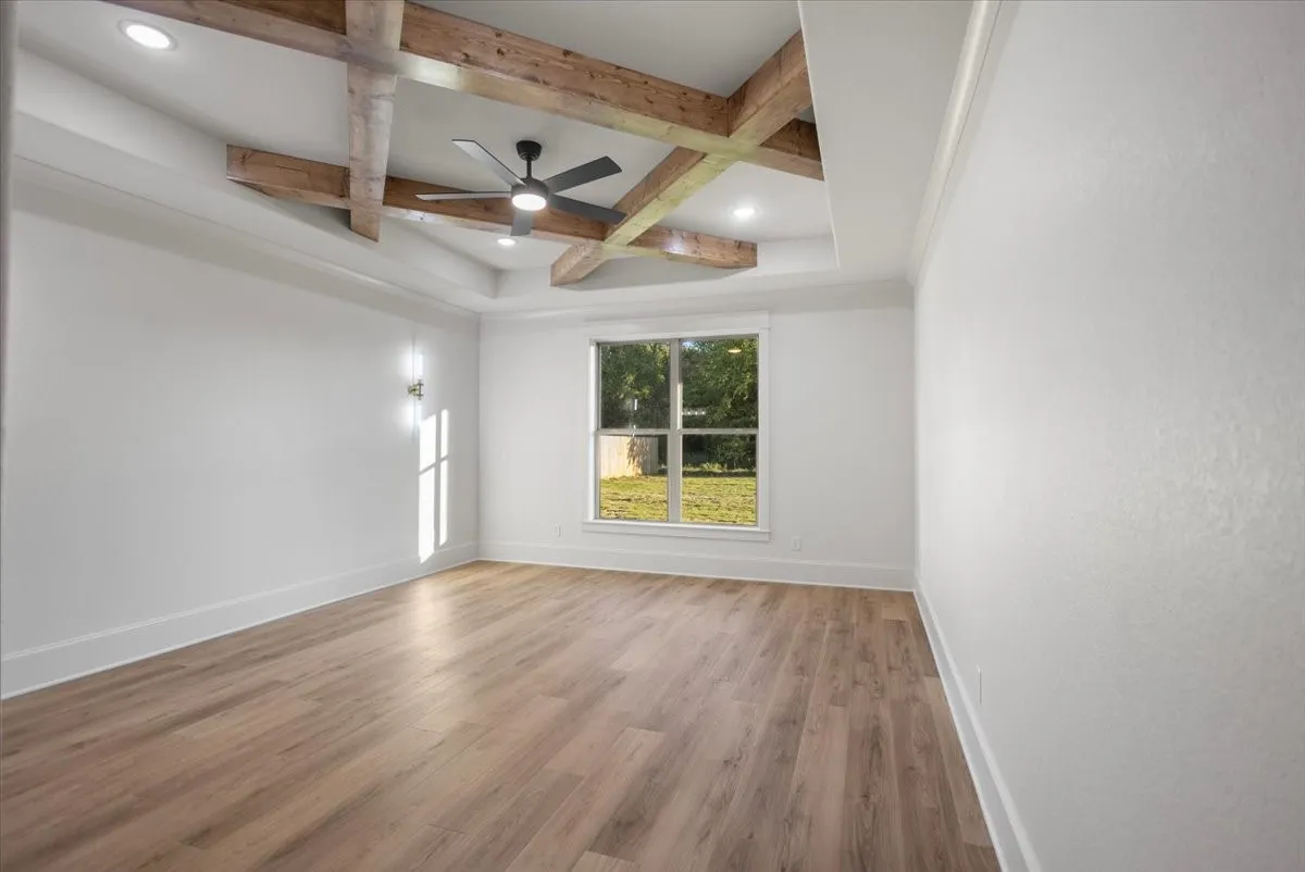 Tray ceiling with wood-finish beams, recessed lighting, and a ceiling fan