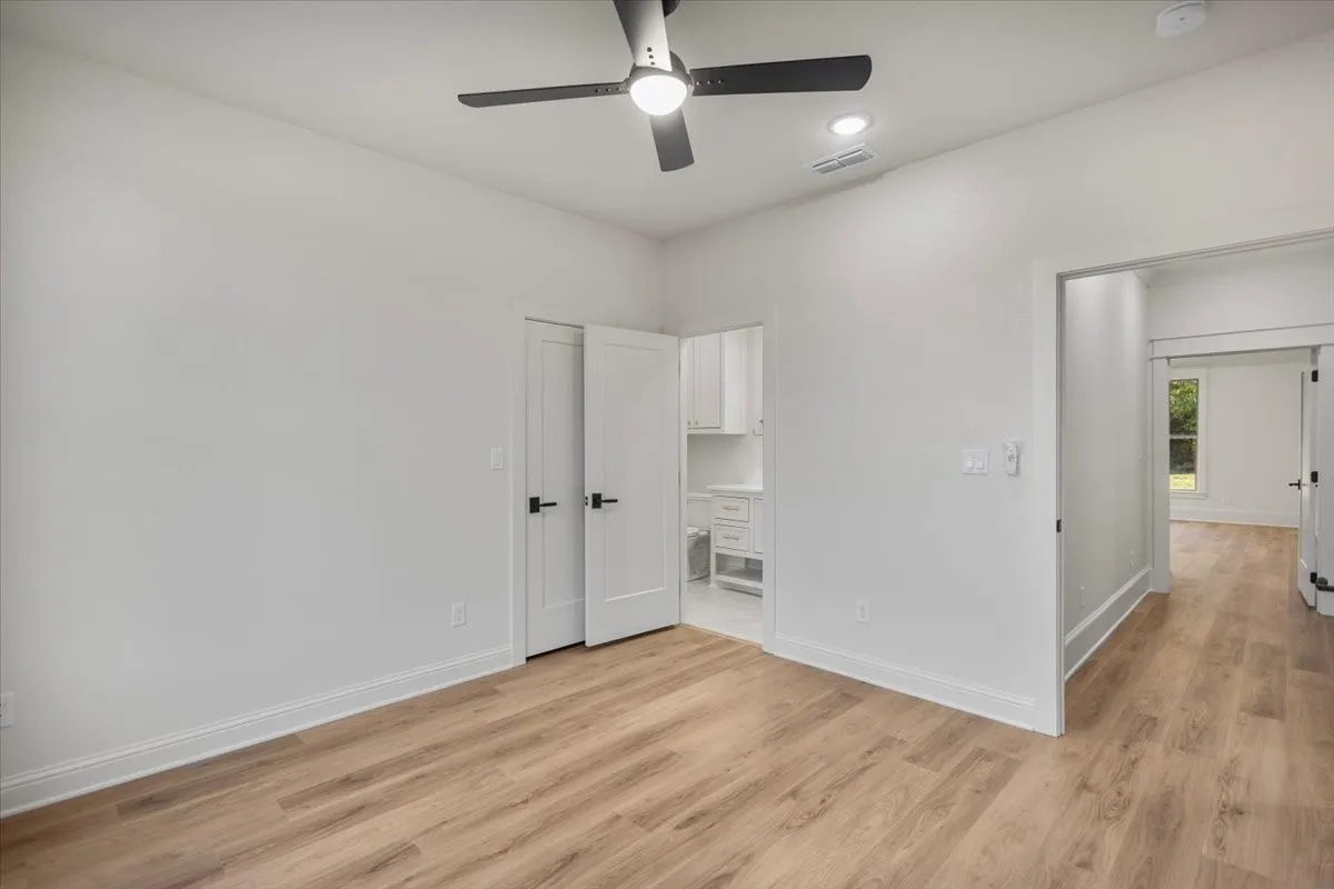 Wood-finish flooring, white walls, and a contemporary ceiling fan with integrated lighting