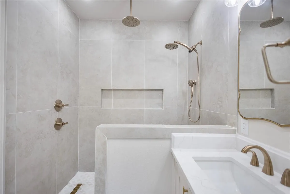 Walk-in shower with light-toned wall tile, built-in shower bench, and recessed shower niches