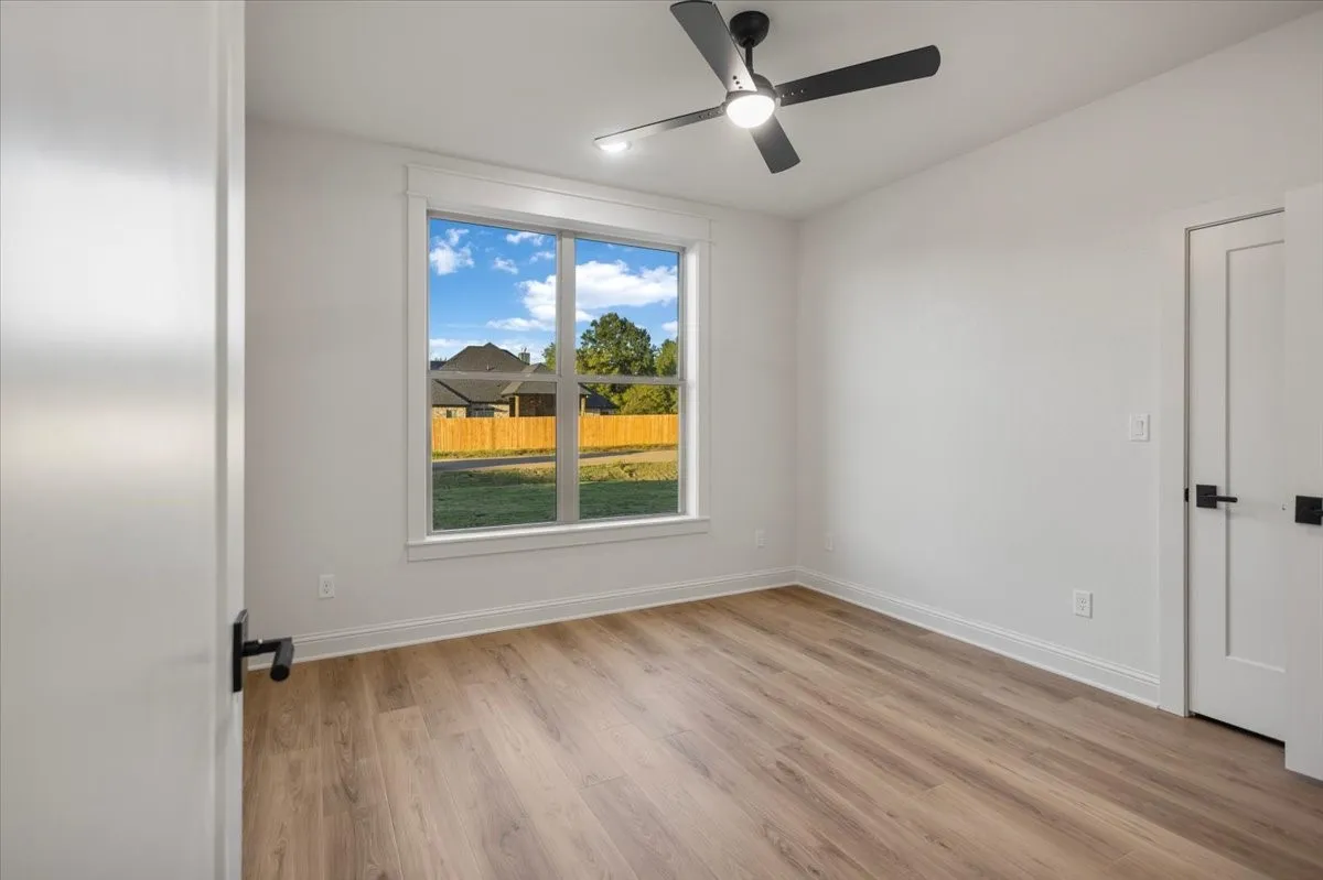Light-filled room featuring wood-finish flooring and a ceiling fan