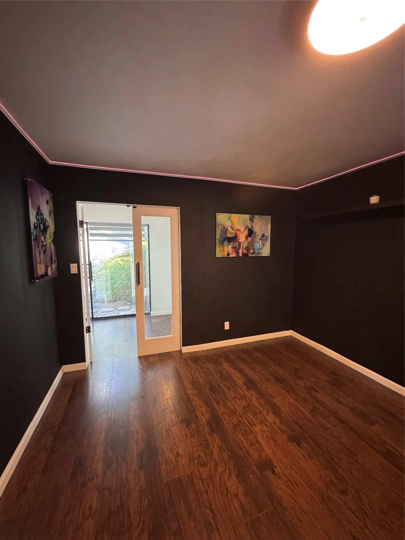 Dark accent wall, wood-finish flooring, white trim, recessed lighting, and a sliding glass door