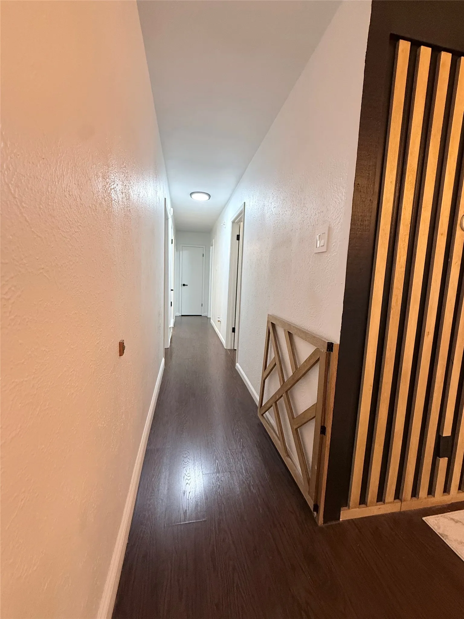 Hallway featuring wood-finish flooring, recessed lighting, and a decorative slatted wall accent