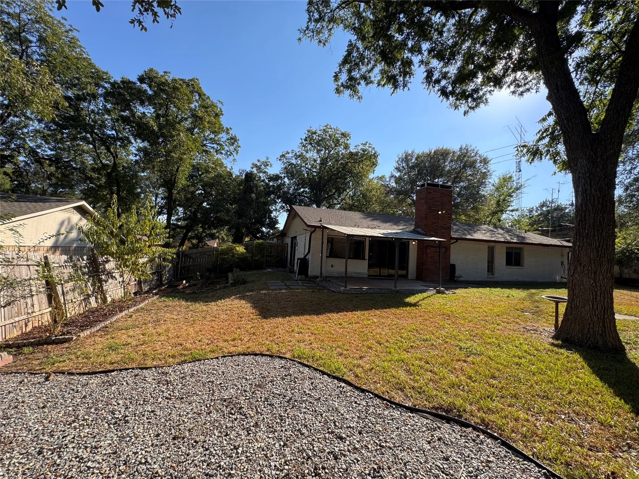Expansive backyard featuring a gravel area, a grass lawn, and mature trees