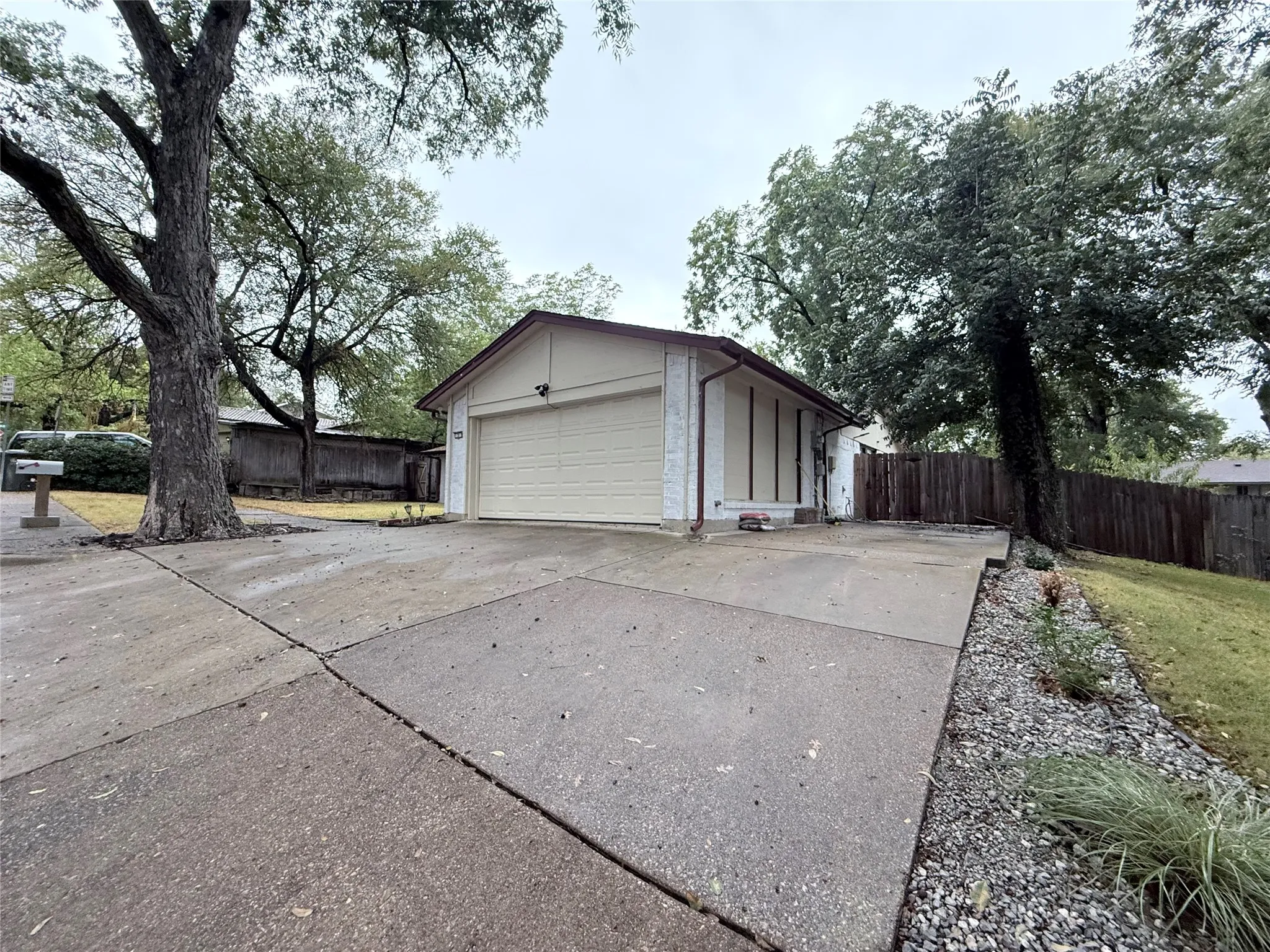 Attached garage with an overhead door, concrete driveway, and mature landscaping