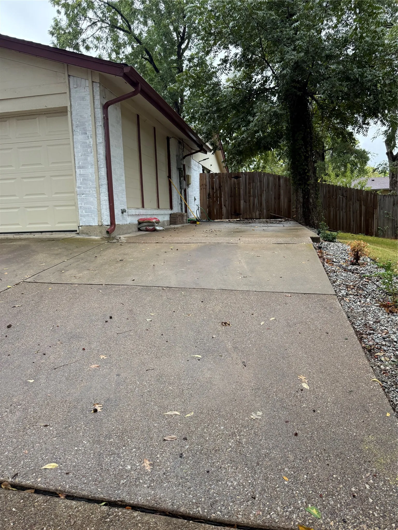 Exterior featuring a two-car garage, white brick facade, and a wood privacy fence