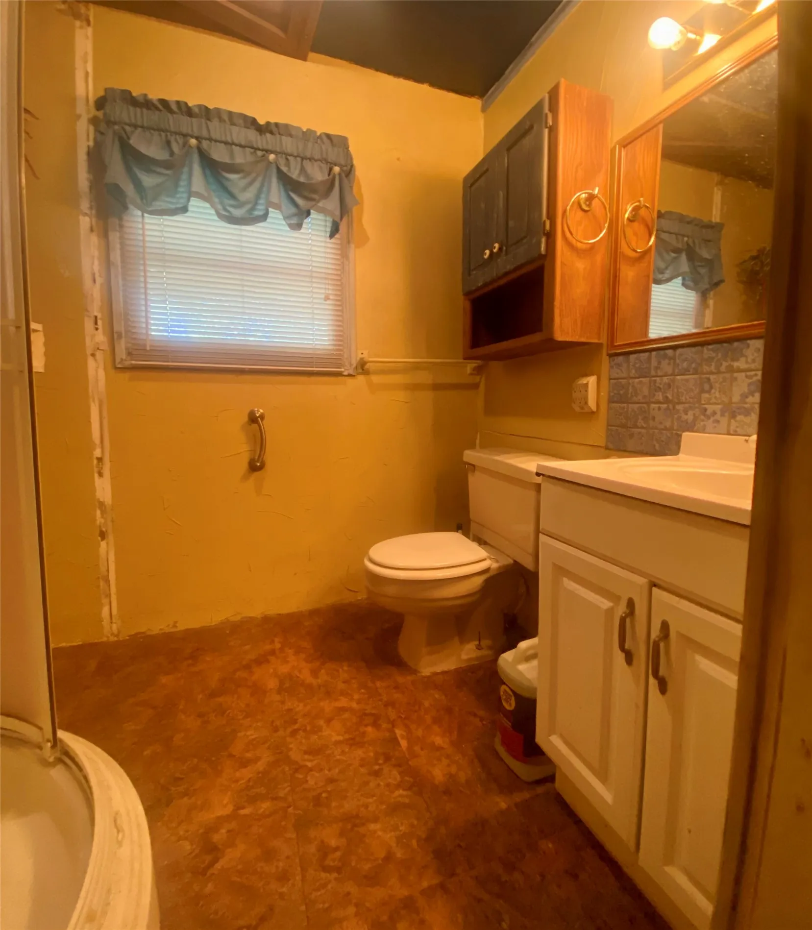 Bathroom with a window, toilet, vanity with cabinet storage, and wall-mounted mirror