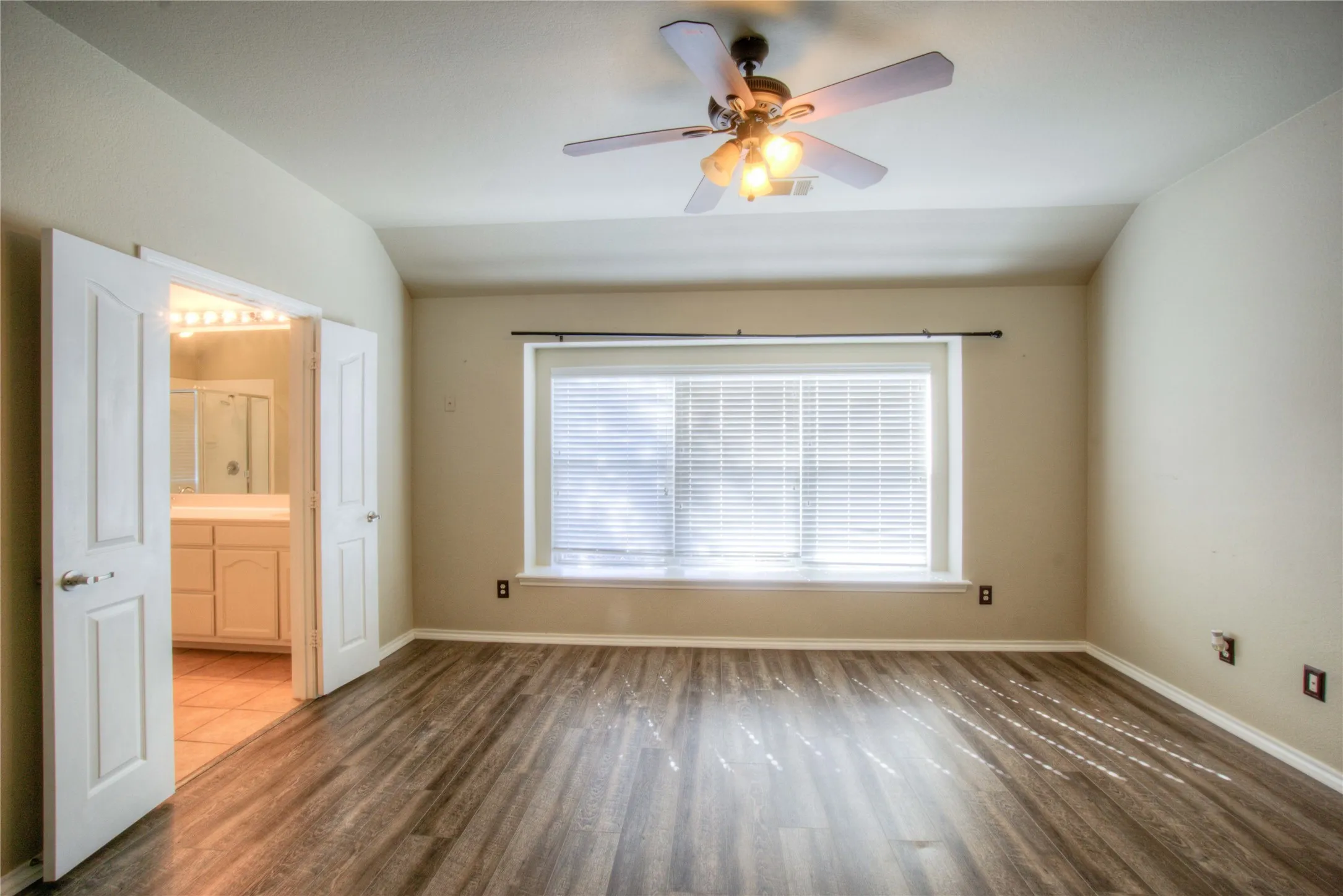 Wood-finish flooring, ceiling fan with integrated lighting, natural light window, and dual entry doors