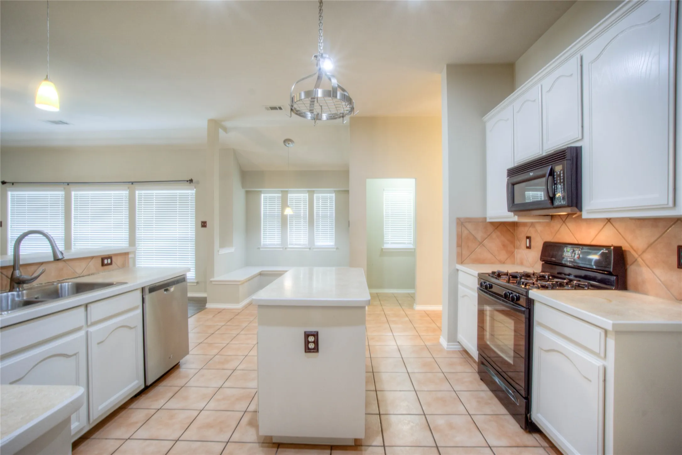 White cabinetry, central island, stainless steel sink, black range, and built-in microwave