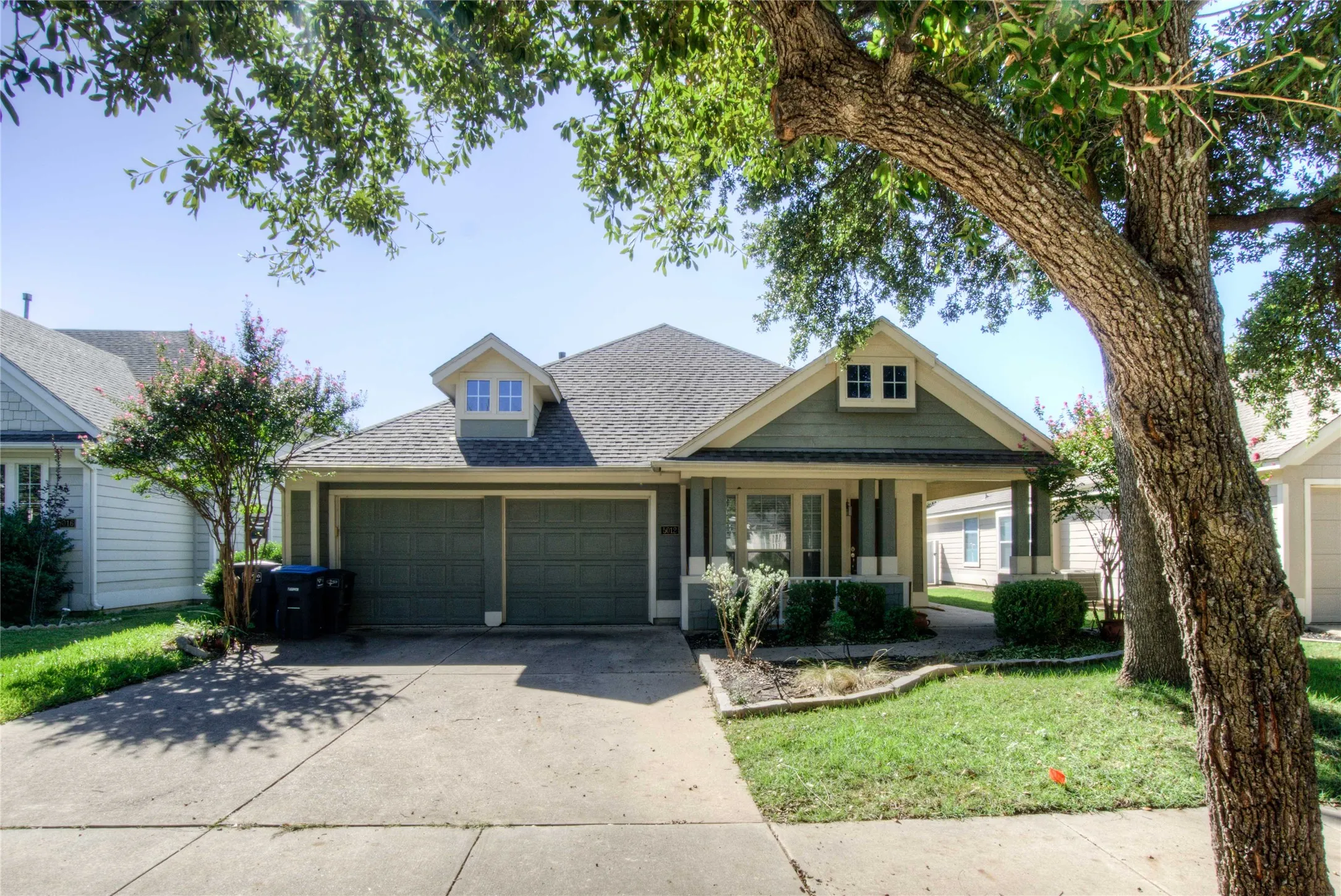 Craftsman-style facade with a covered front porch, dual dormer windows, and an attached two-car garage