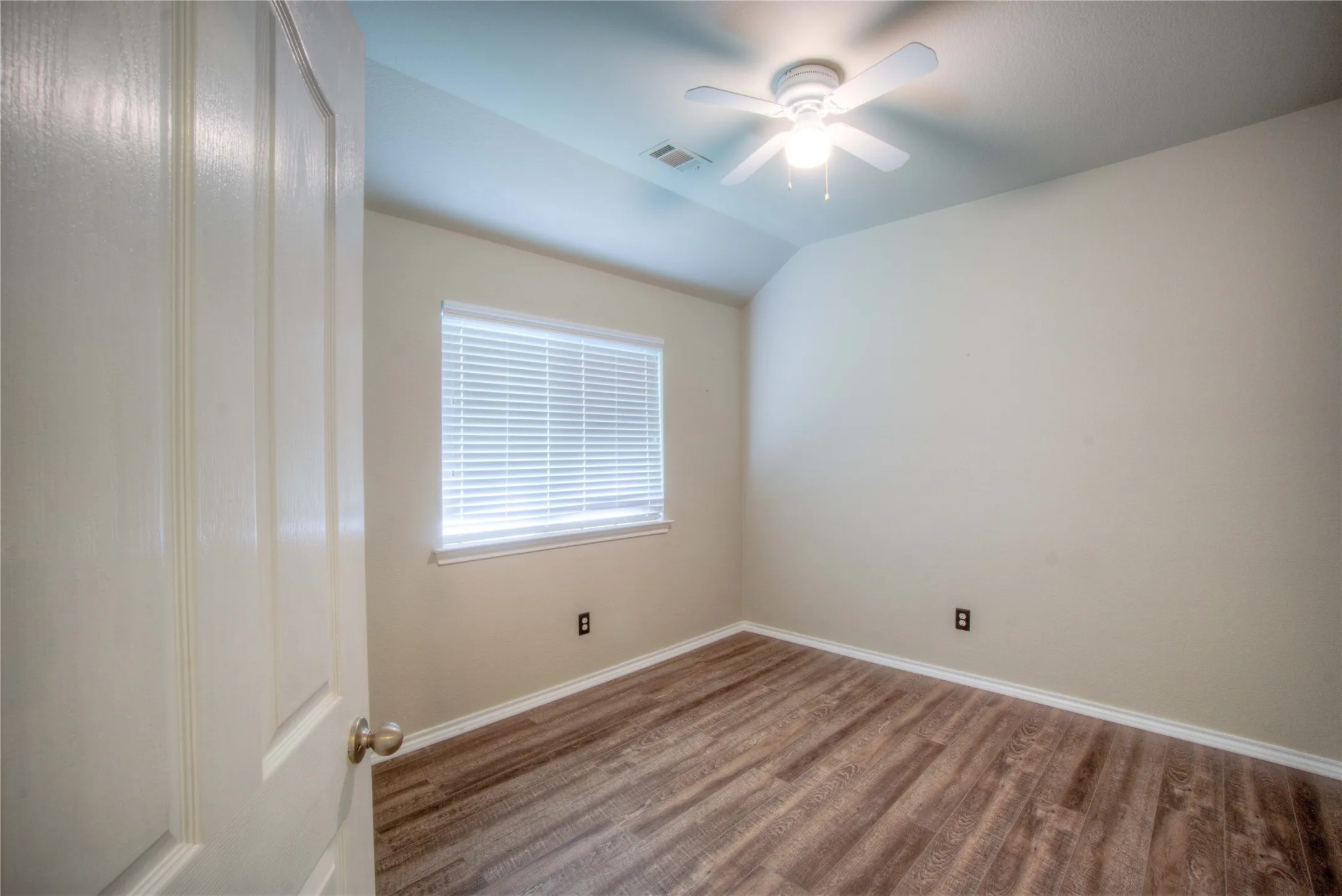 Wood-finish flooring, single window with blinds, ceiling fan, and sloped ceiling