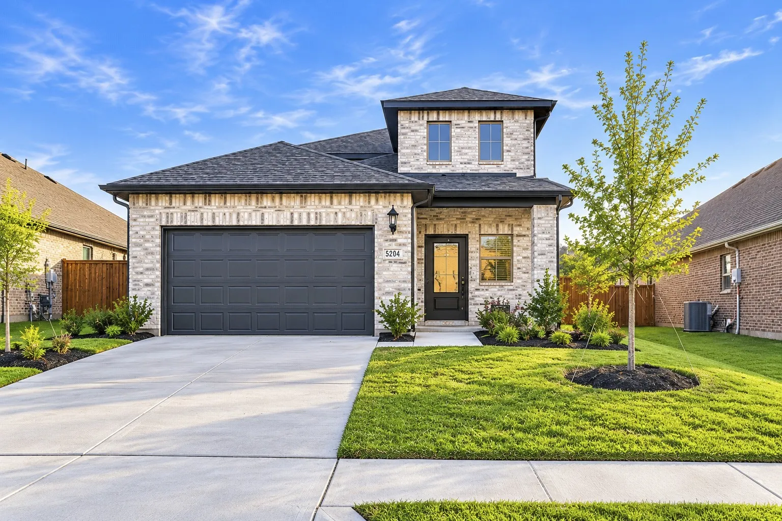 Brick veneer exterior with dark shingle roof and covered entry