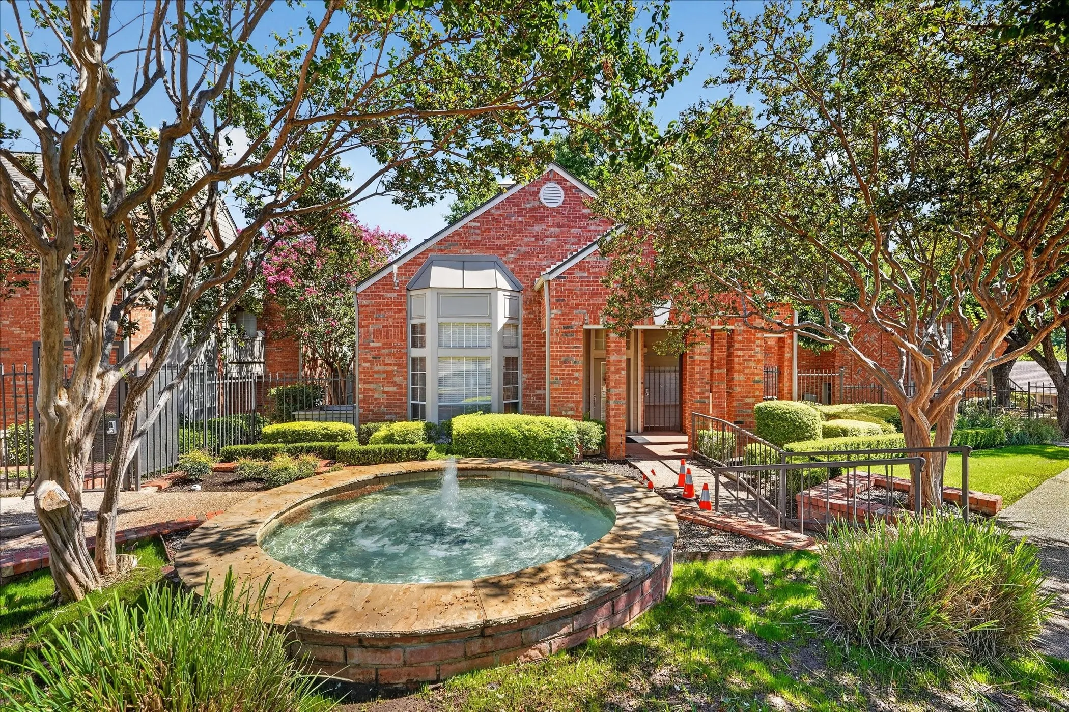Red brick exterior with a prominent arched window and a decorative fountain