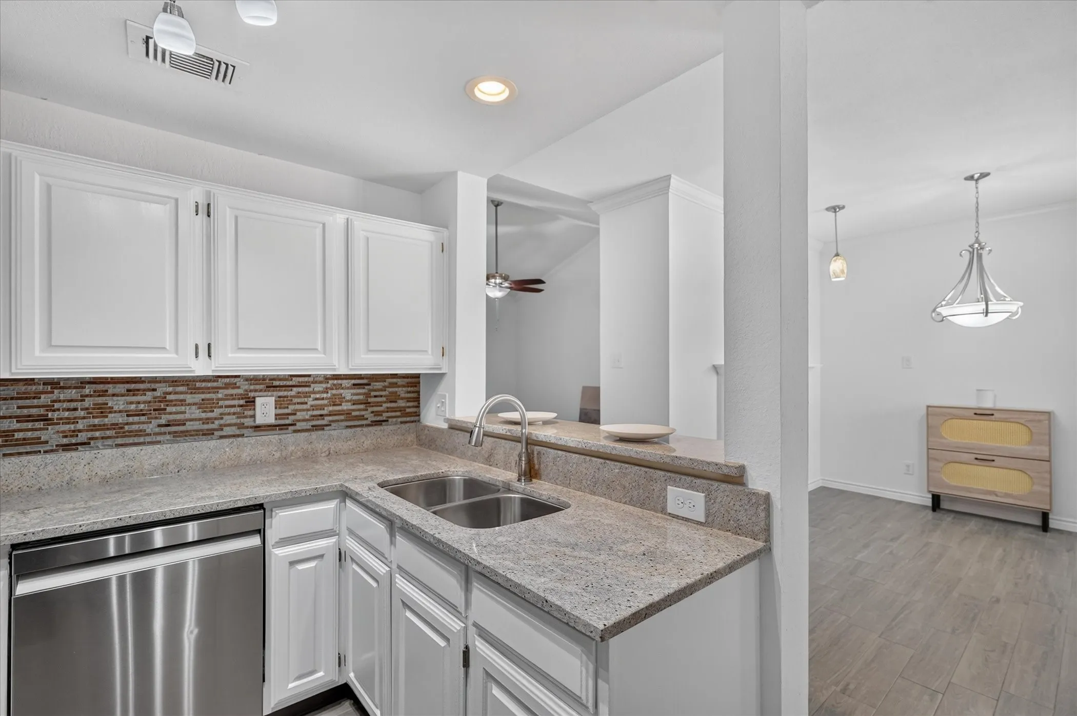 Kitchen featuring white cabinetry, stone countertops, mosaic tile backsplash, stainless steel dishwasher, and a double basin sink with a gooseneck faucet