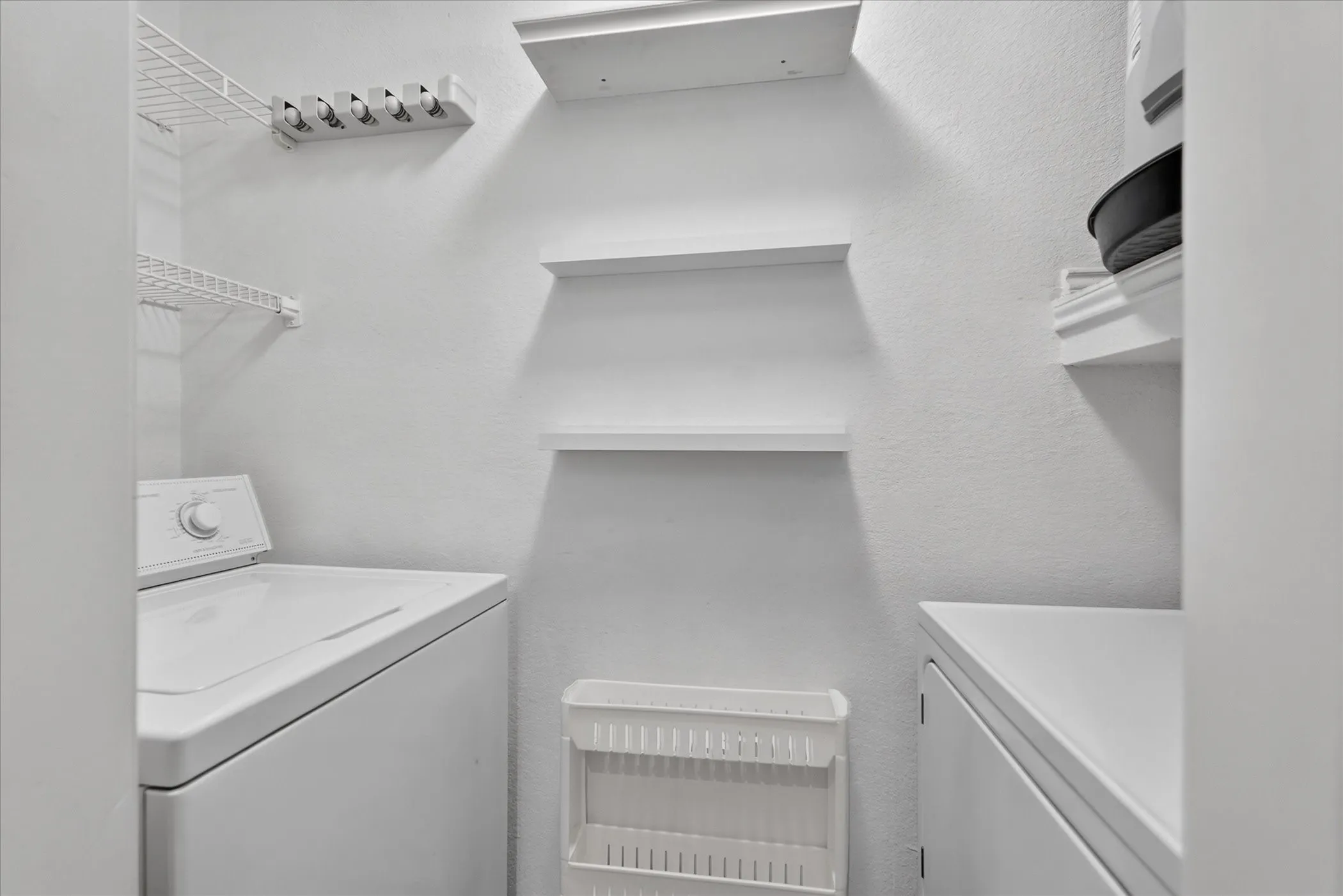 White wall-mounted wire shelving, white wall-mounted floating shelves, and a white wall-mounted organizing rack