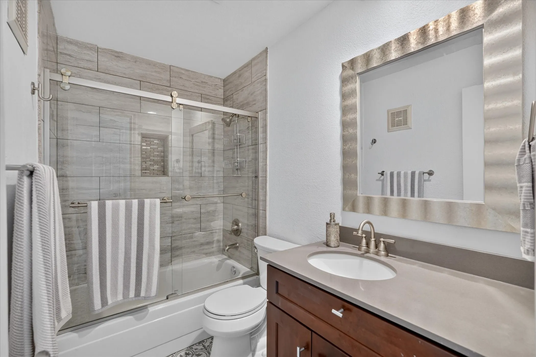 Bathroom featuring a tub/shower combination with tile surround, glass sliding door, and a built-in shower niche