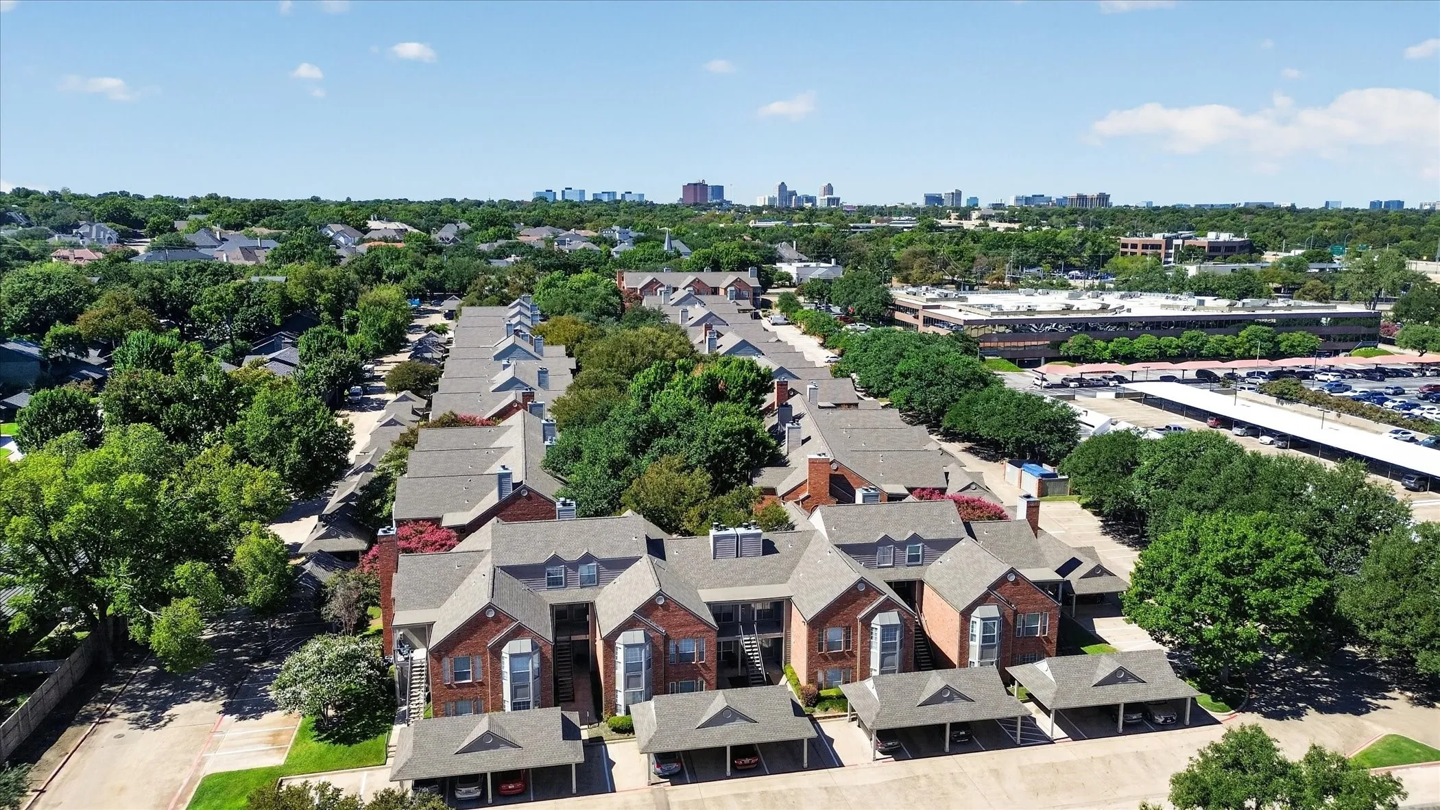 Brick exterior construction with dormer windows, covered parking, and mature landscaping