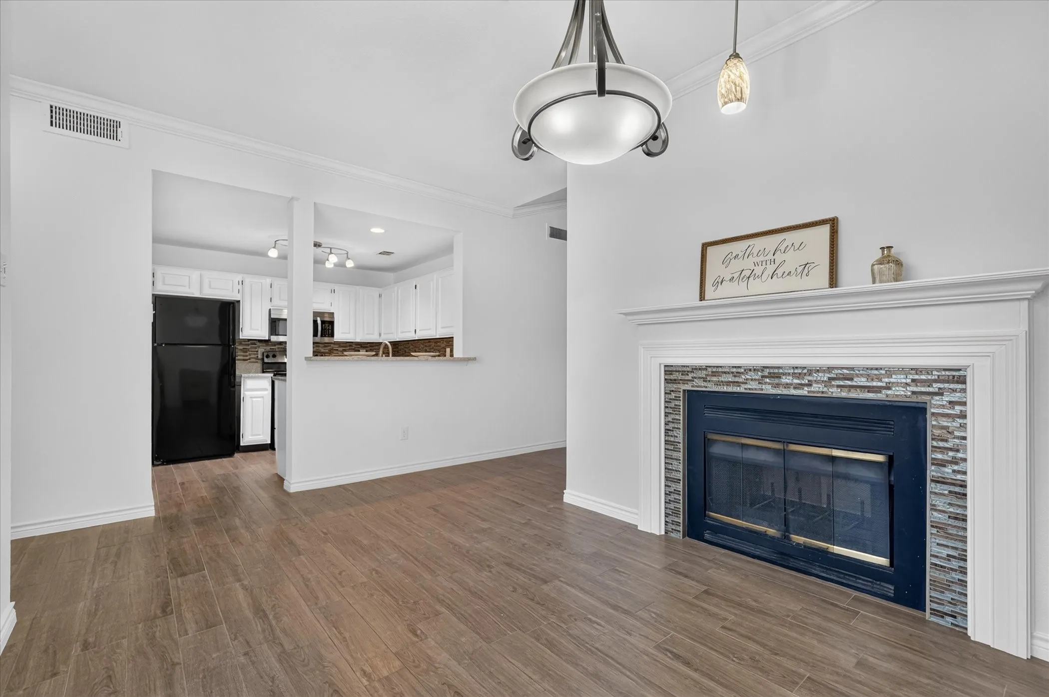 Wood-finish flooring, white walls, and a fireplace with a tile surround and white mantel