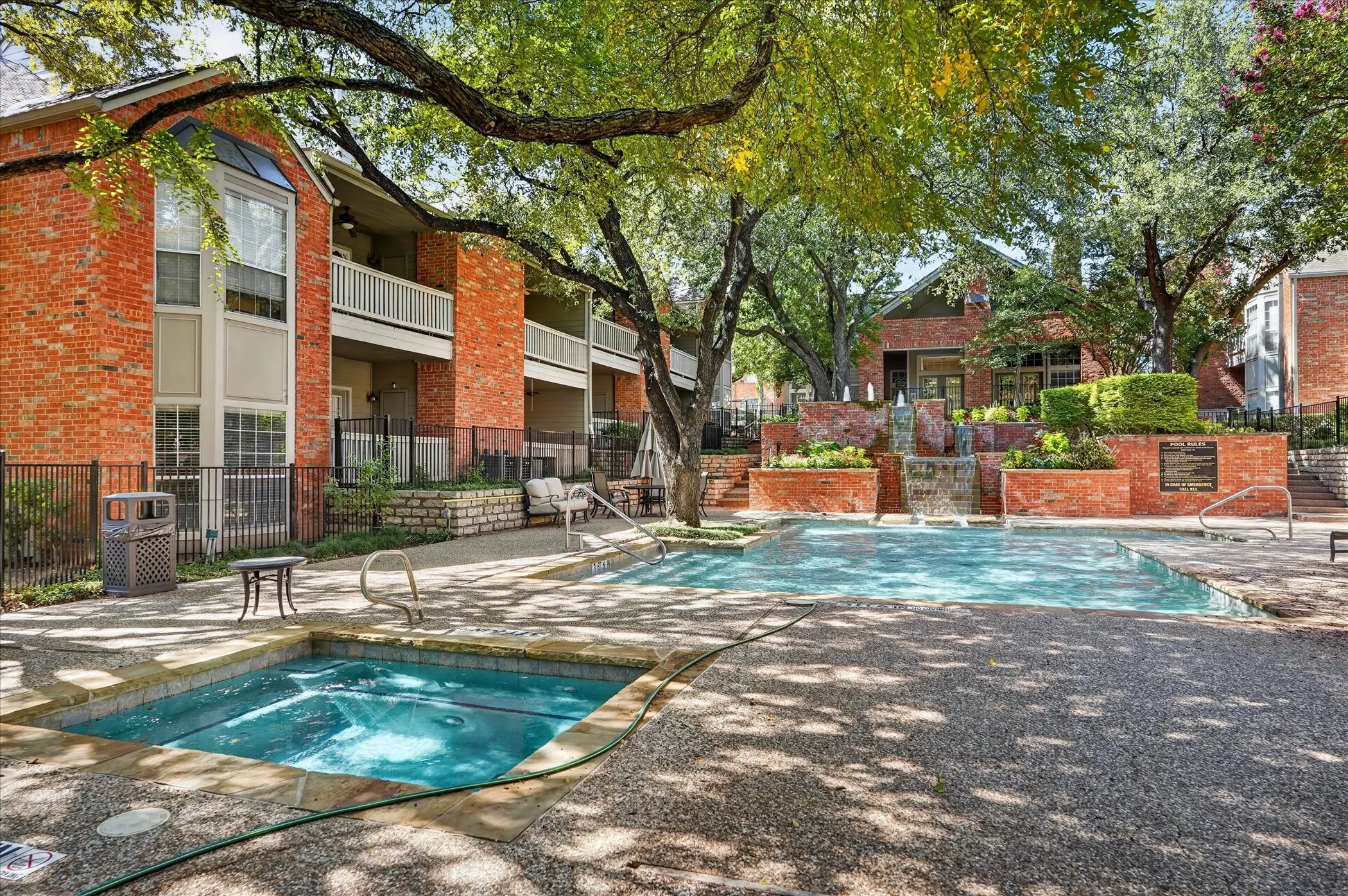 Pool deck featuring a swimming pool, integrated spa, and a multi-tiered water feature