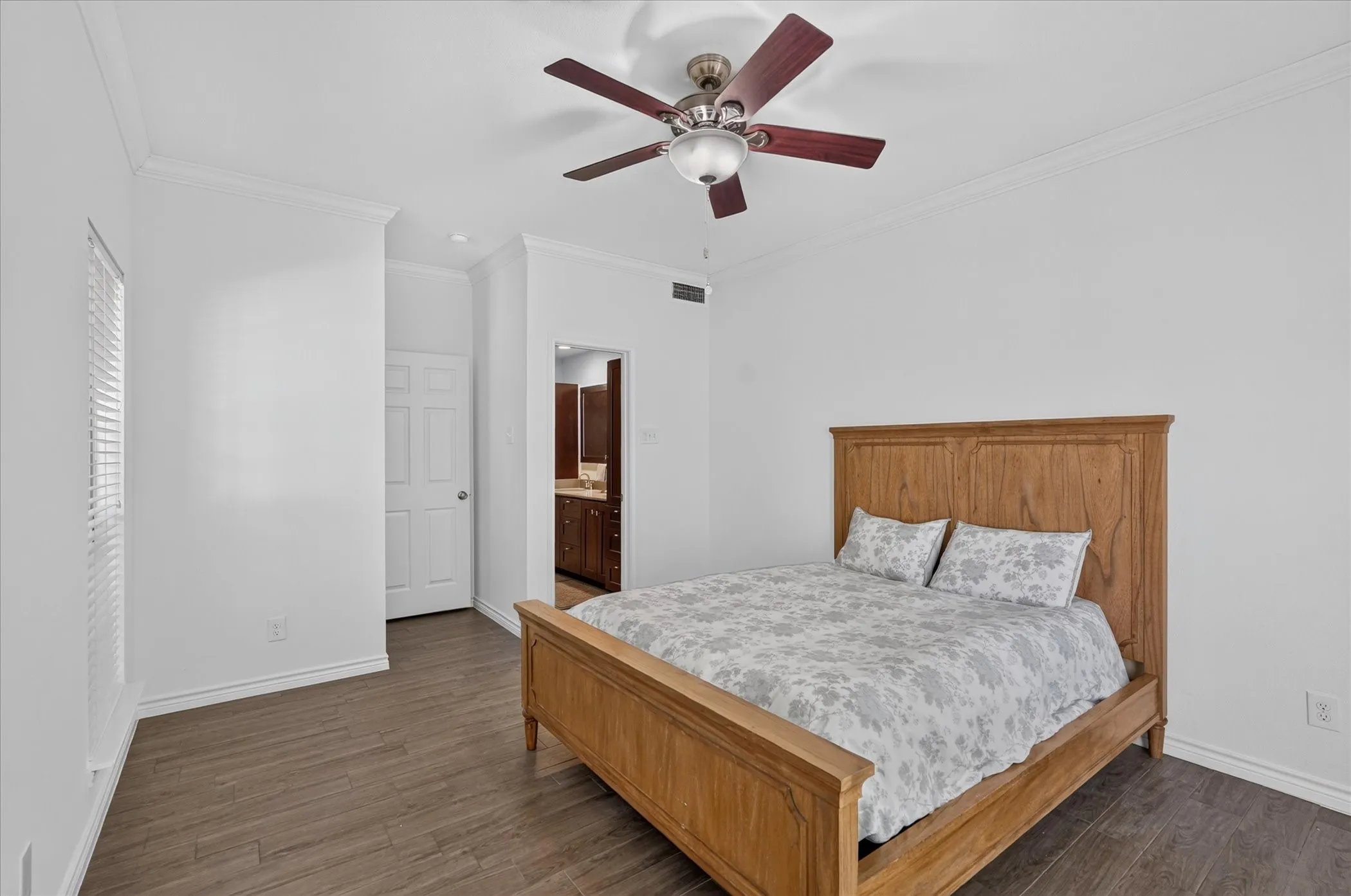 Wood-finish flooring, crown molding, ceiling fan, white paneled door, and recessed lighting