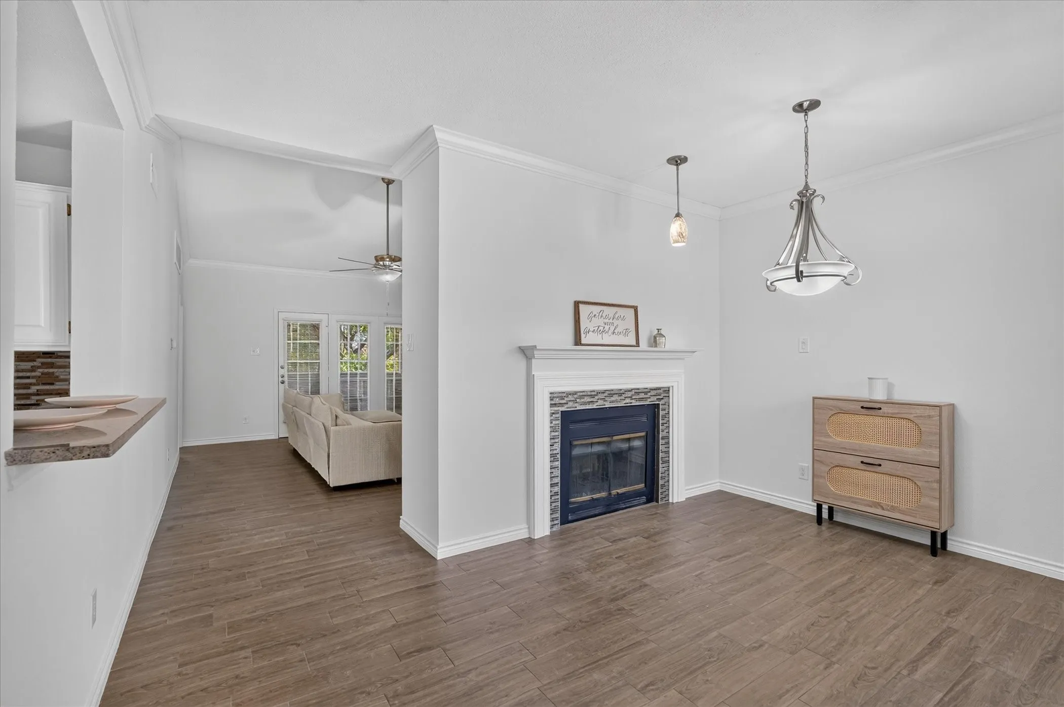 Wood-finish flooring throughout, a fireplace with a tiled surround and mantel, and crown molding