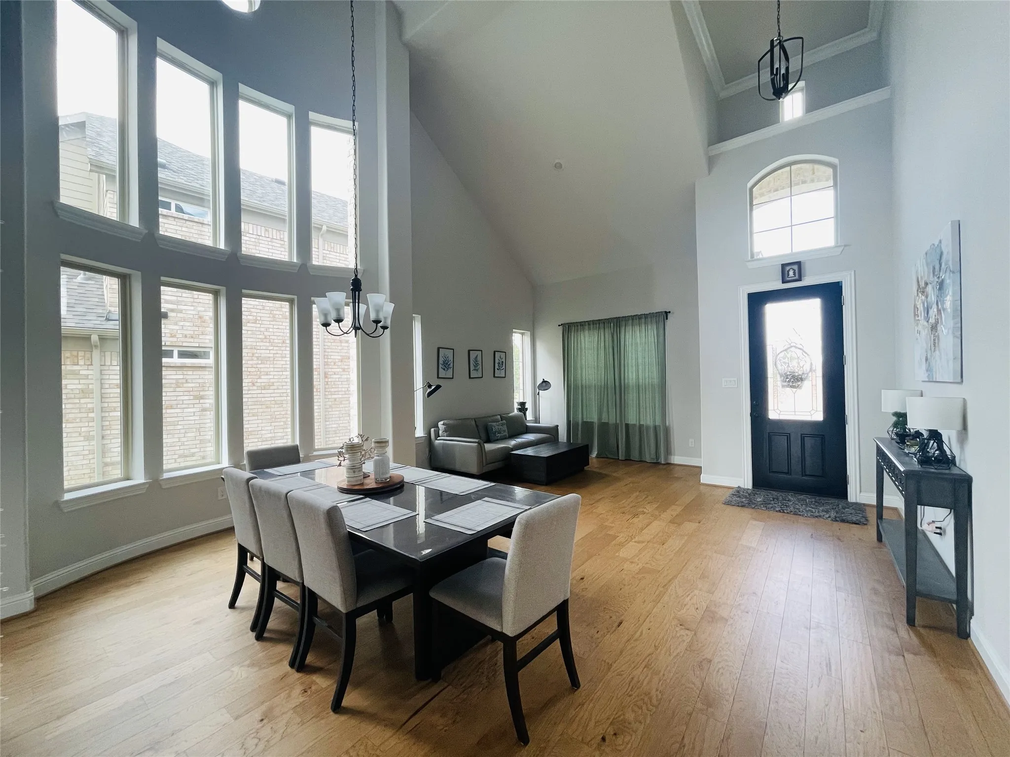 Dining area featuring light hardwood / wood-style flooring, ornamental molding, a high ceiling, and an inviting chandelier