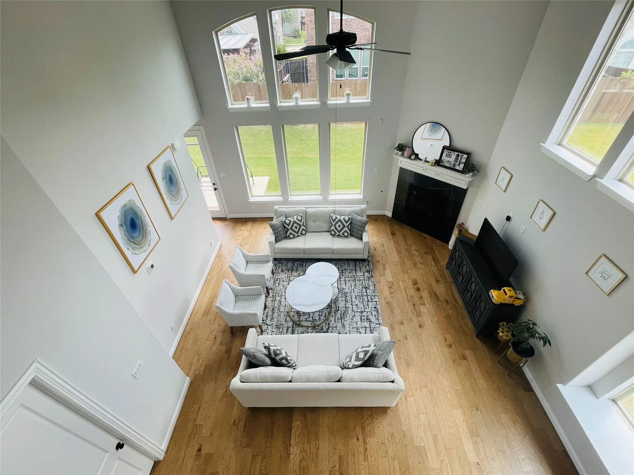 Living room with ceiling fan, wood-type flooring, and a towering ceiling
