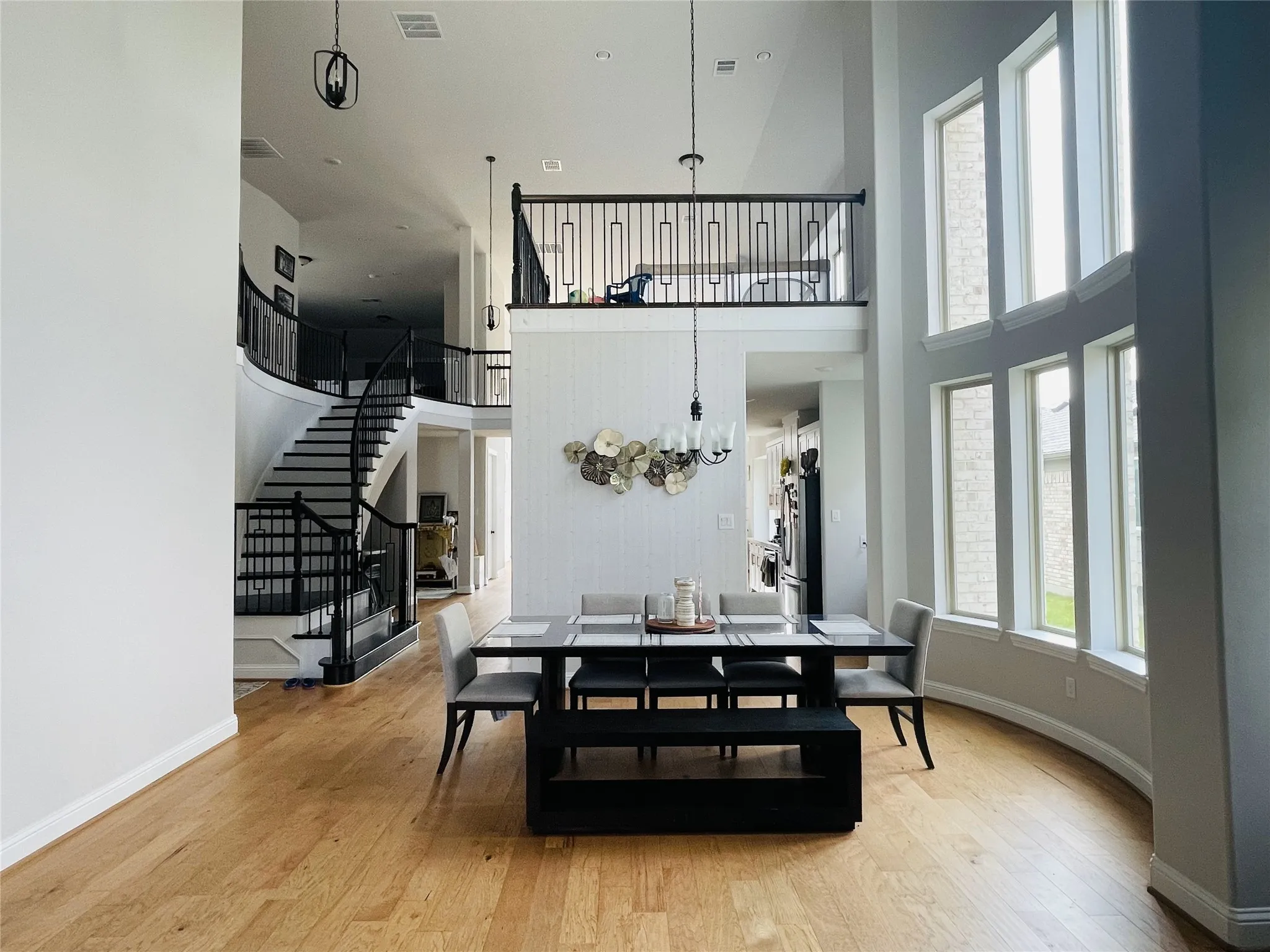 Dining room featuring light wood-type flooring, a towering ceiling, and a chandelier