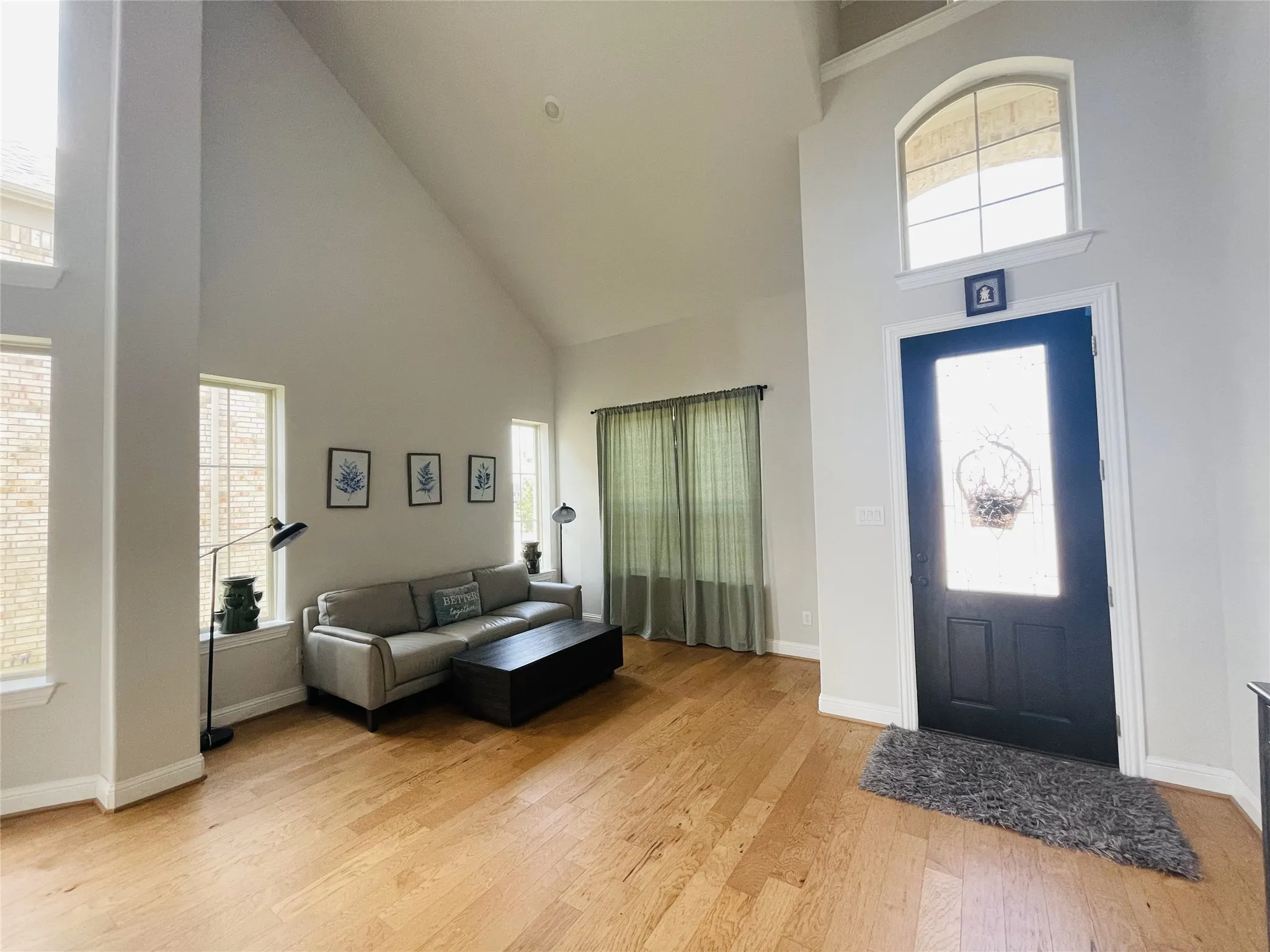 Foyer with light hardwood / wood-style floors and a towering ceiling