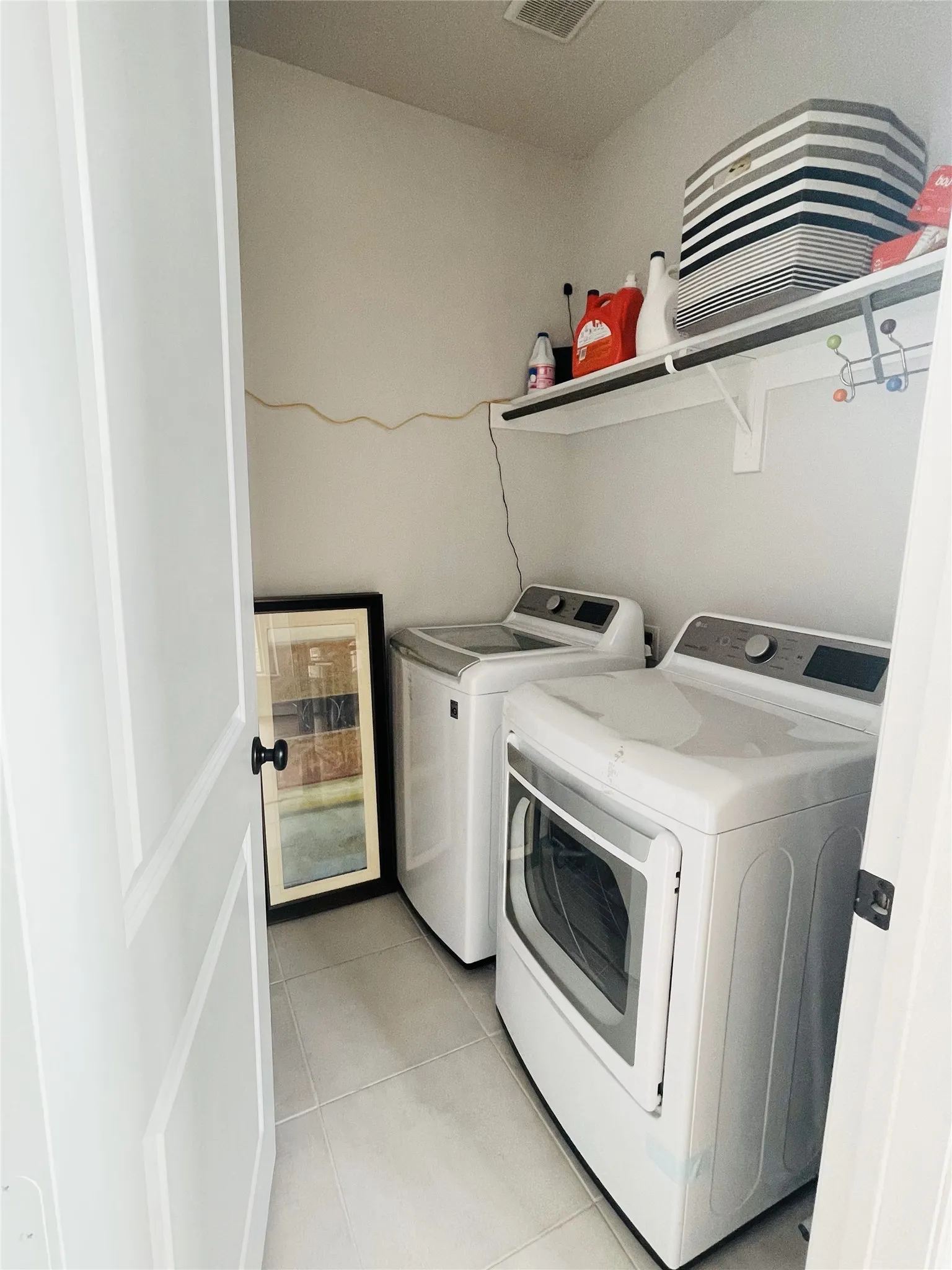Laundry area with light tile patterned floors and washing machine and clothes dryer