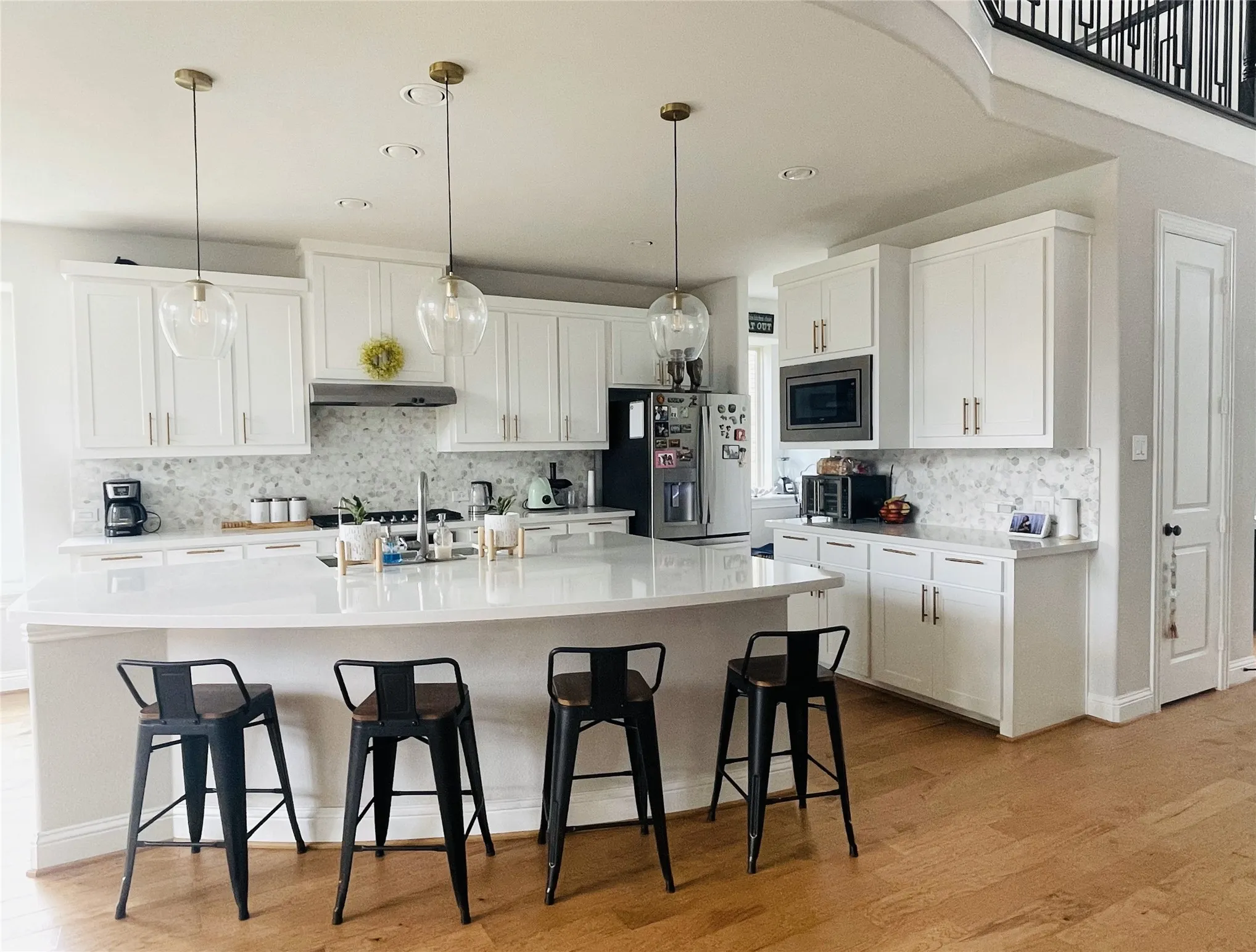 Kitchen with a kitchen bar, appliances with stainless steel finishes, a center island with sink, and white cabinetry