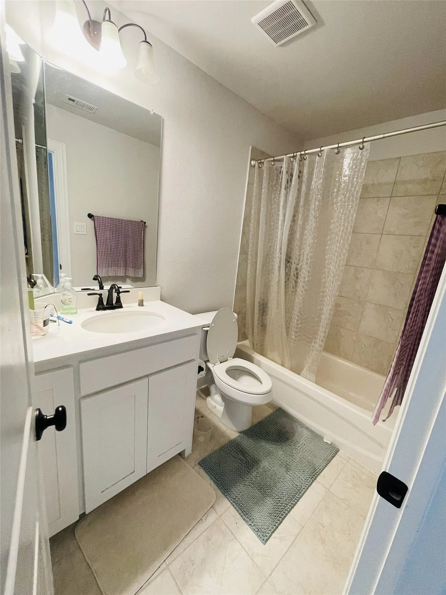 Full bathroom with tile patterned flooring, vanity, toilet, and shower / bathtub combination with curtain
