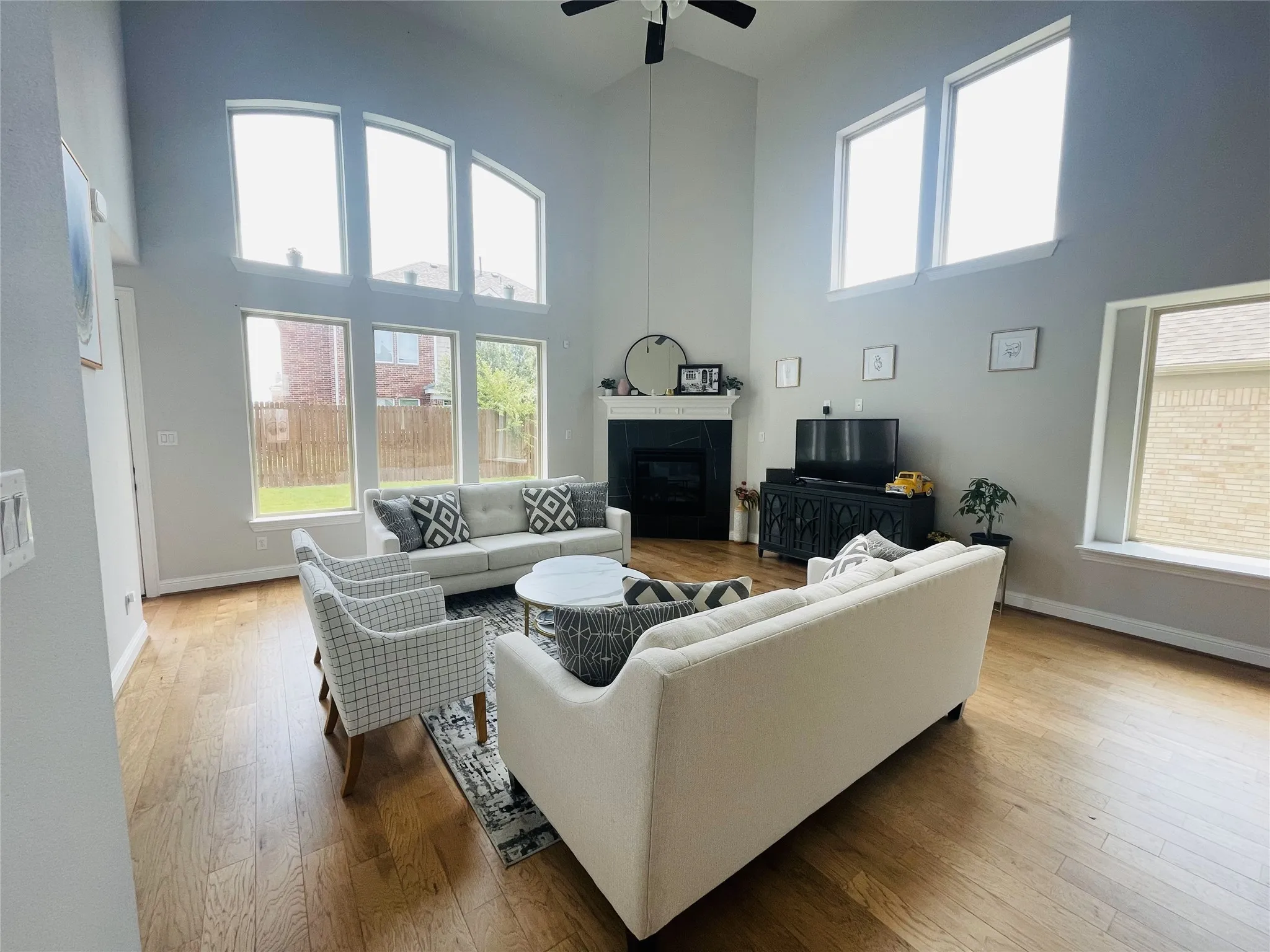 Living room featuring ceiling fan, a towering ceiling, and wood-type flooring