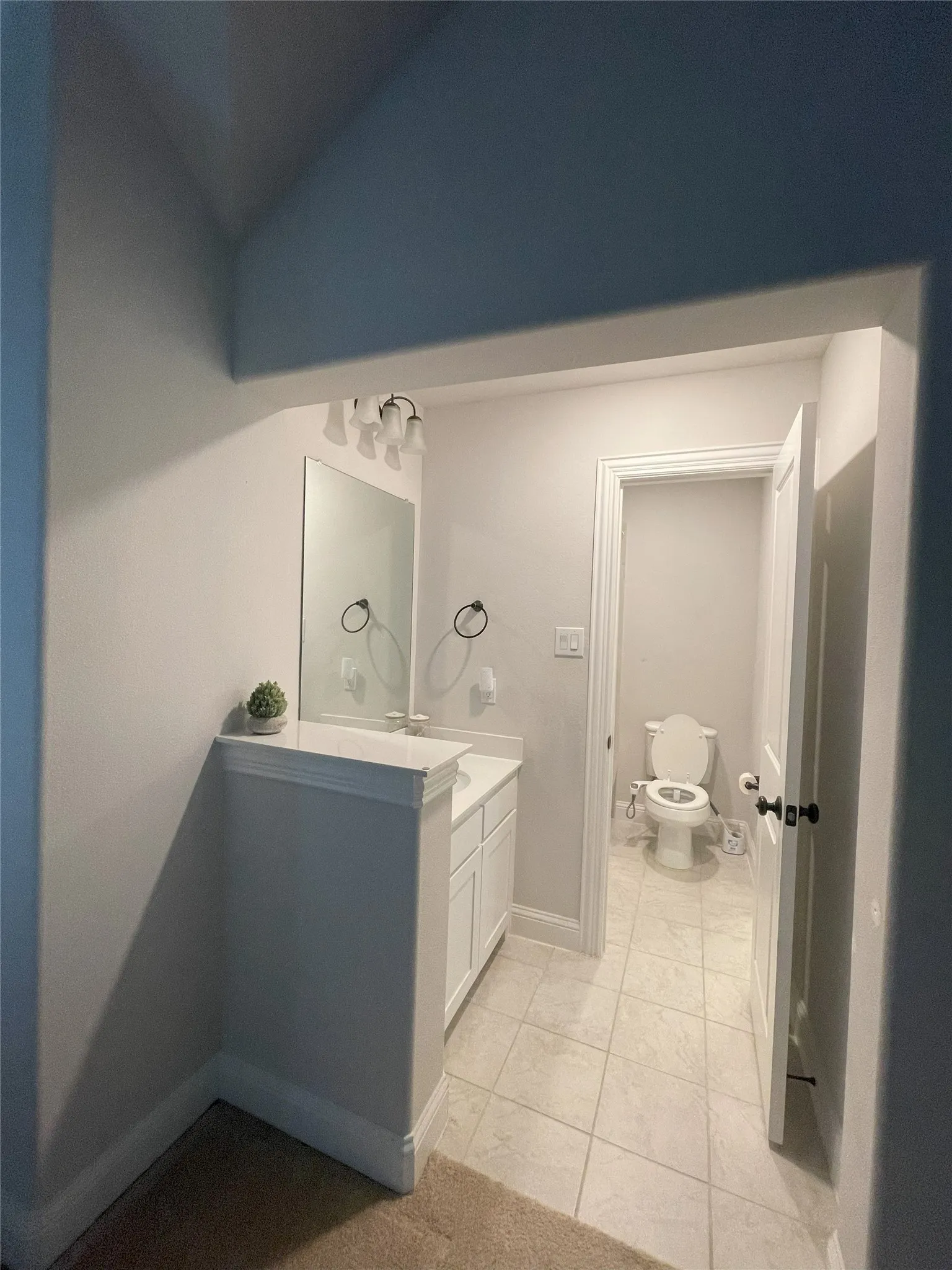 Bathroom with tile patterned floors, vanity, toilet, and vaulted ceiling