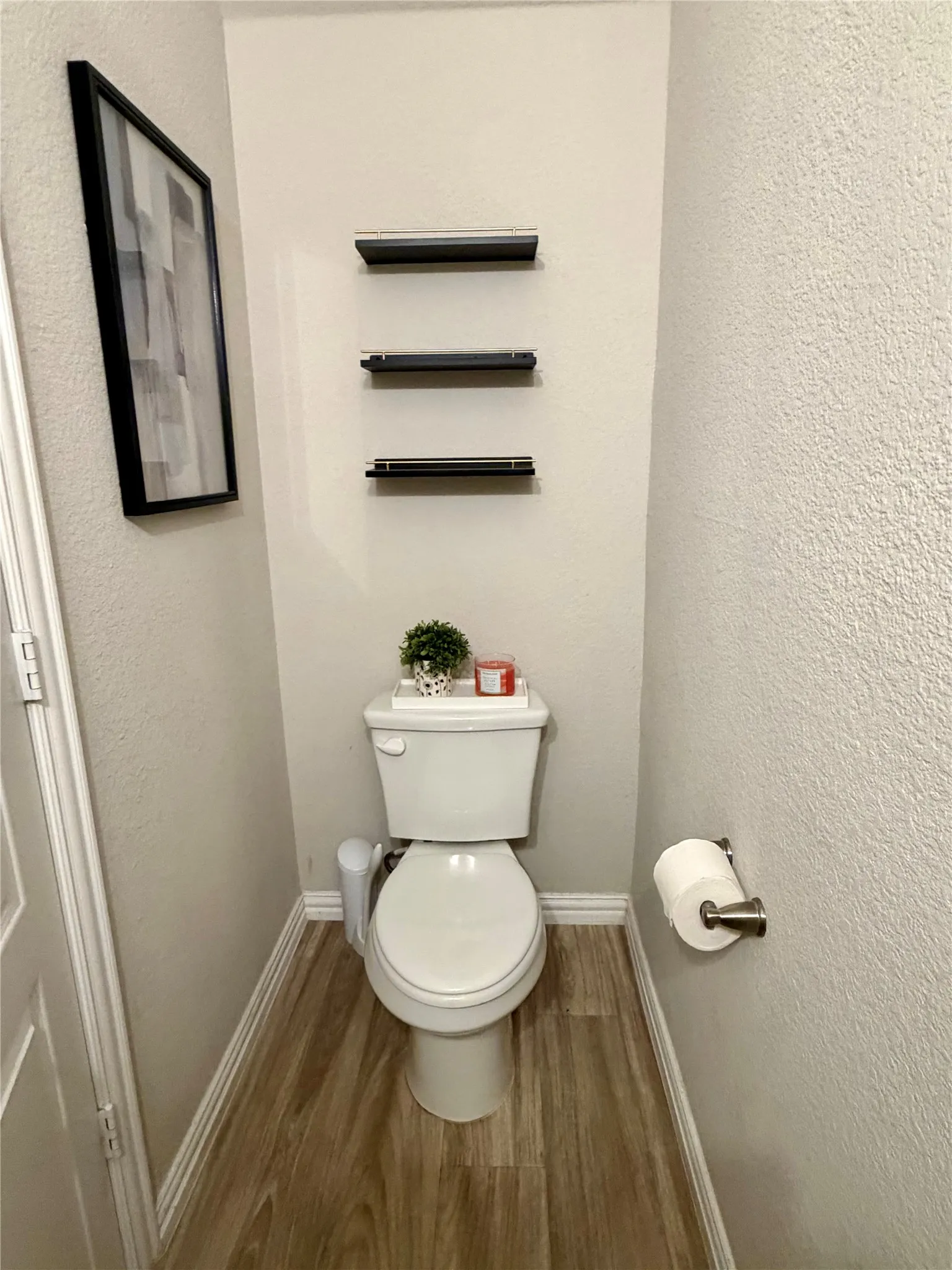 Wood-finish flooring, white baseboards, and wall-mounted shelving