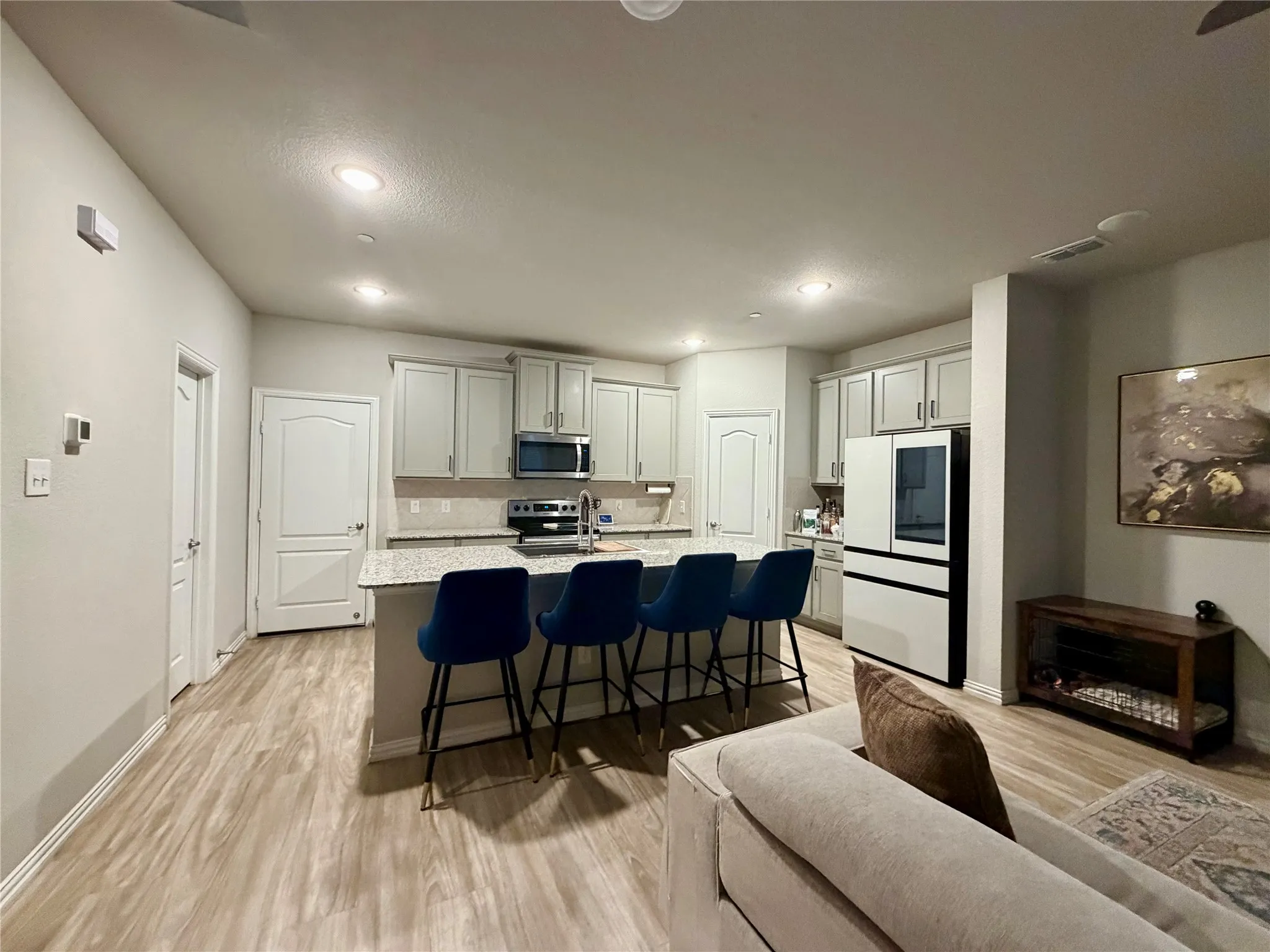 Kitchen with a central island featuring a granite countertop, light wood-finish flooring, recessed lighting, and white cabinetry