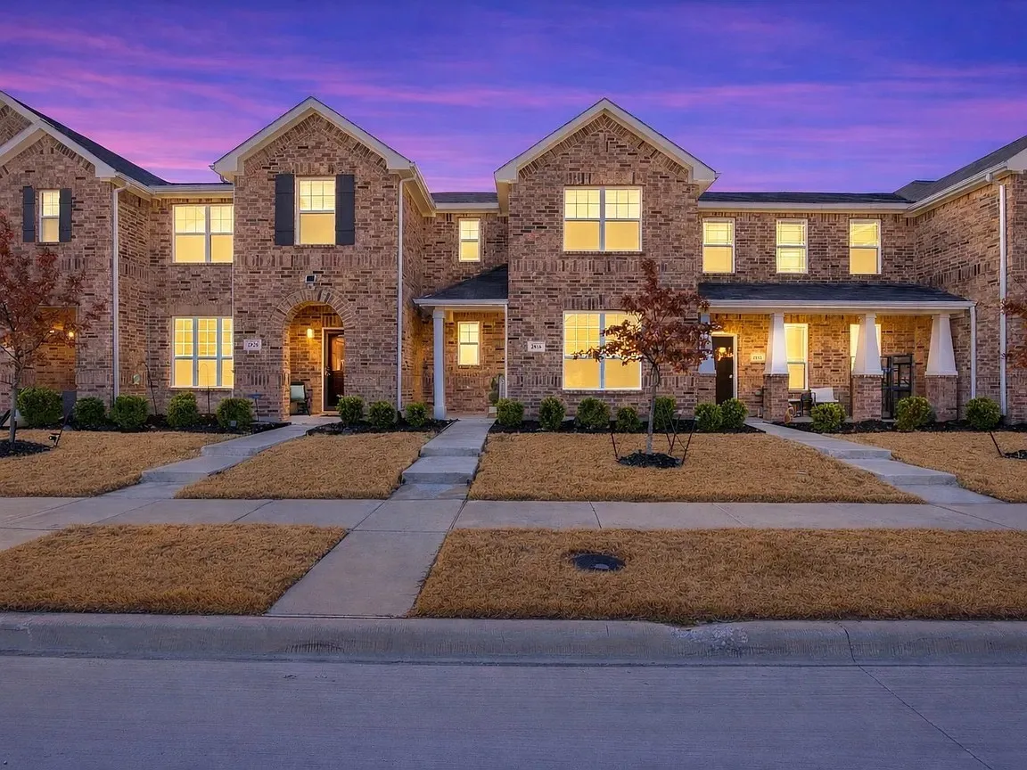 Brick exterior construction, arched entryway, covered porch, multiple windows with dark shutters, paved walkways