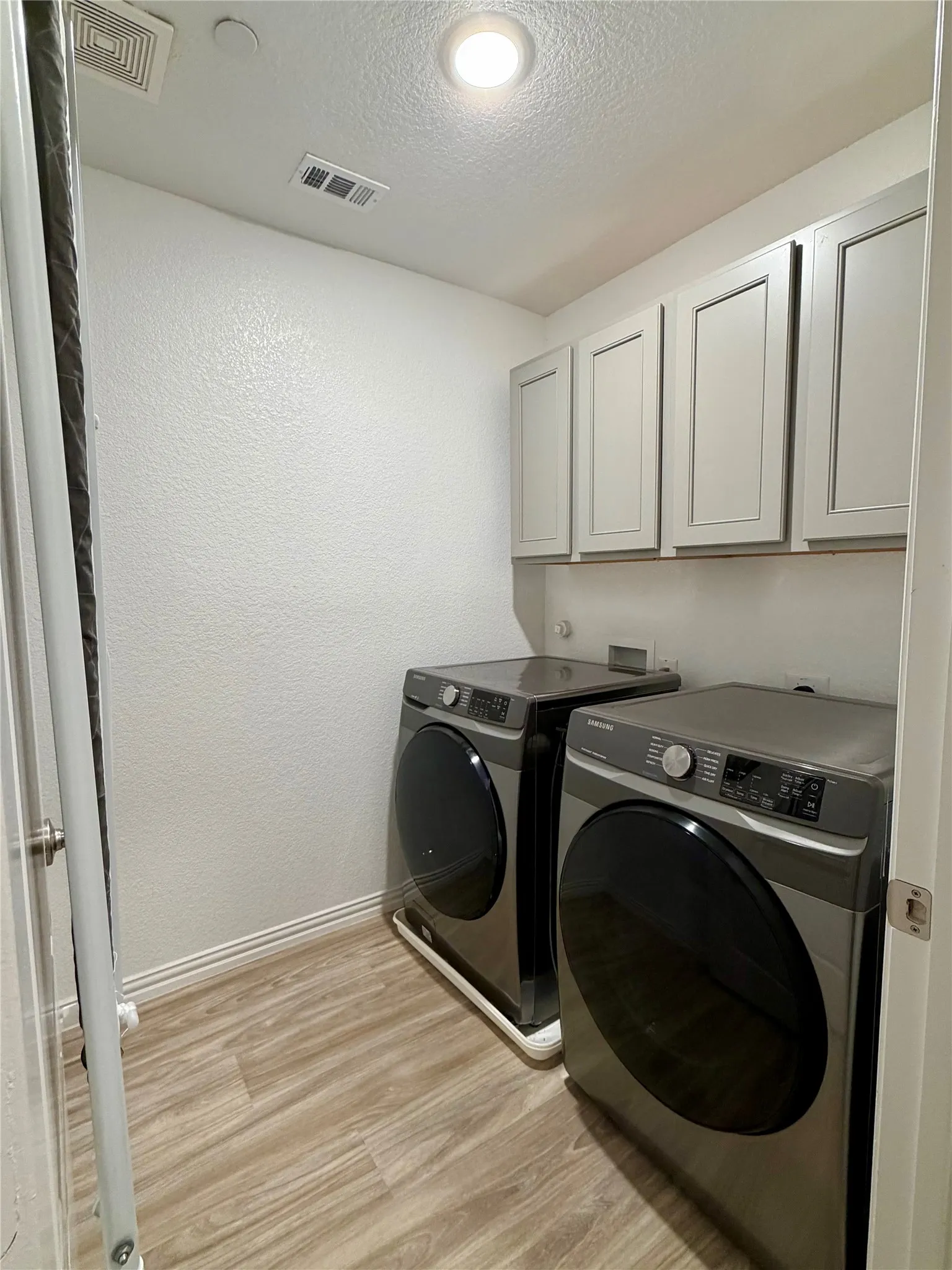 Recessed ceiling lighting, wood-finish flooring, white walls, and built-in upper cabinetry