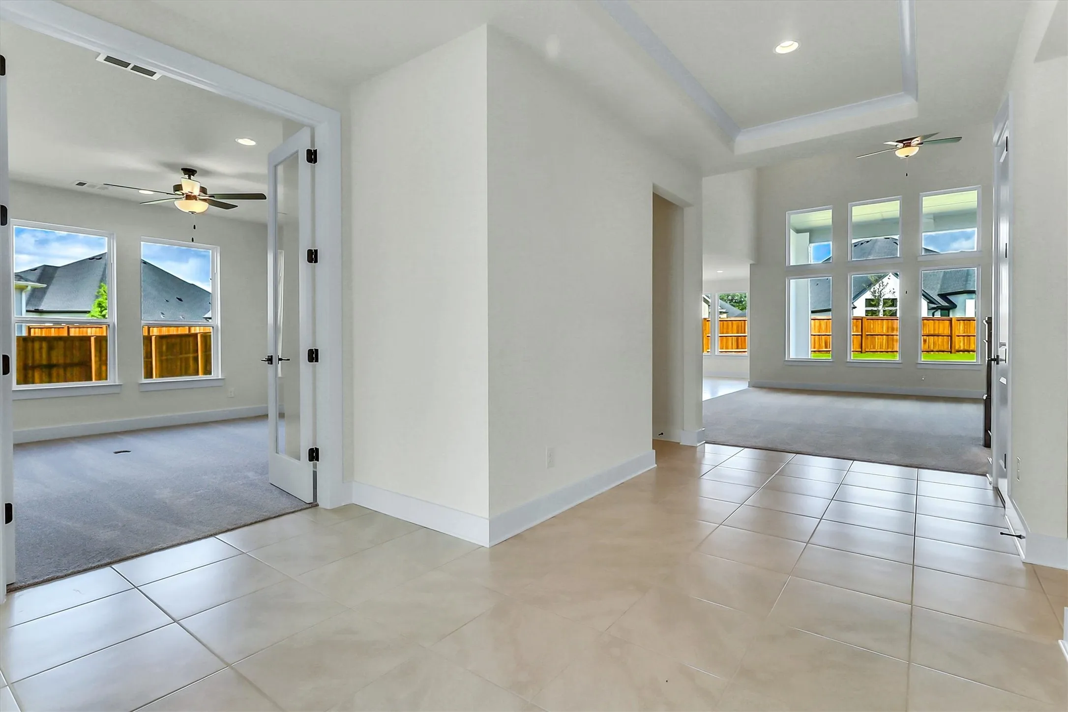 Tile flooring, tray ceiling, recessed lighting, ceiling fan, and large windows