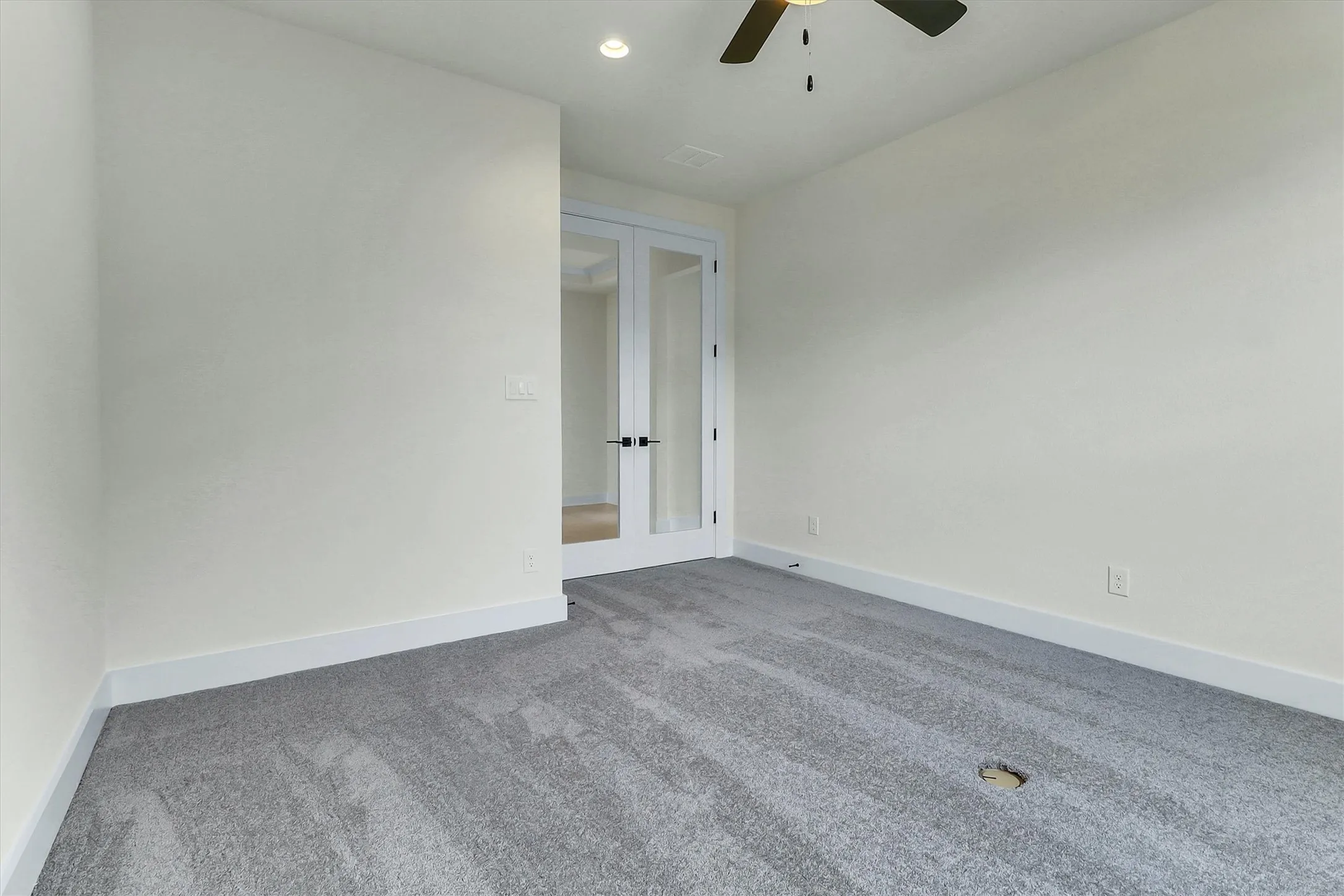 Light gray carpeting with recessed lighting and a ceiling fan