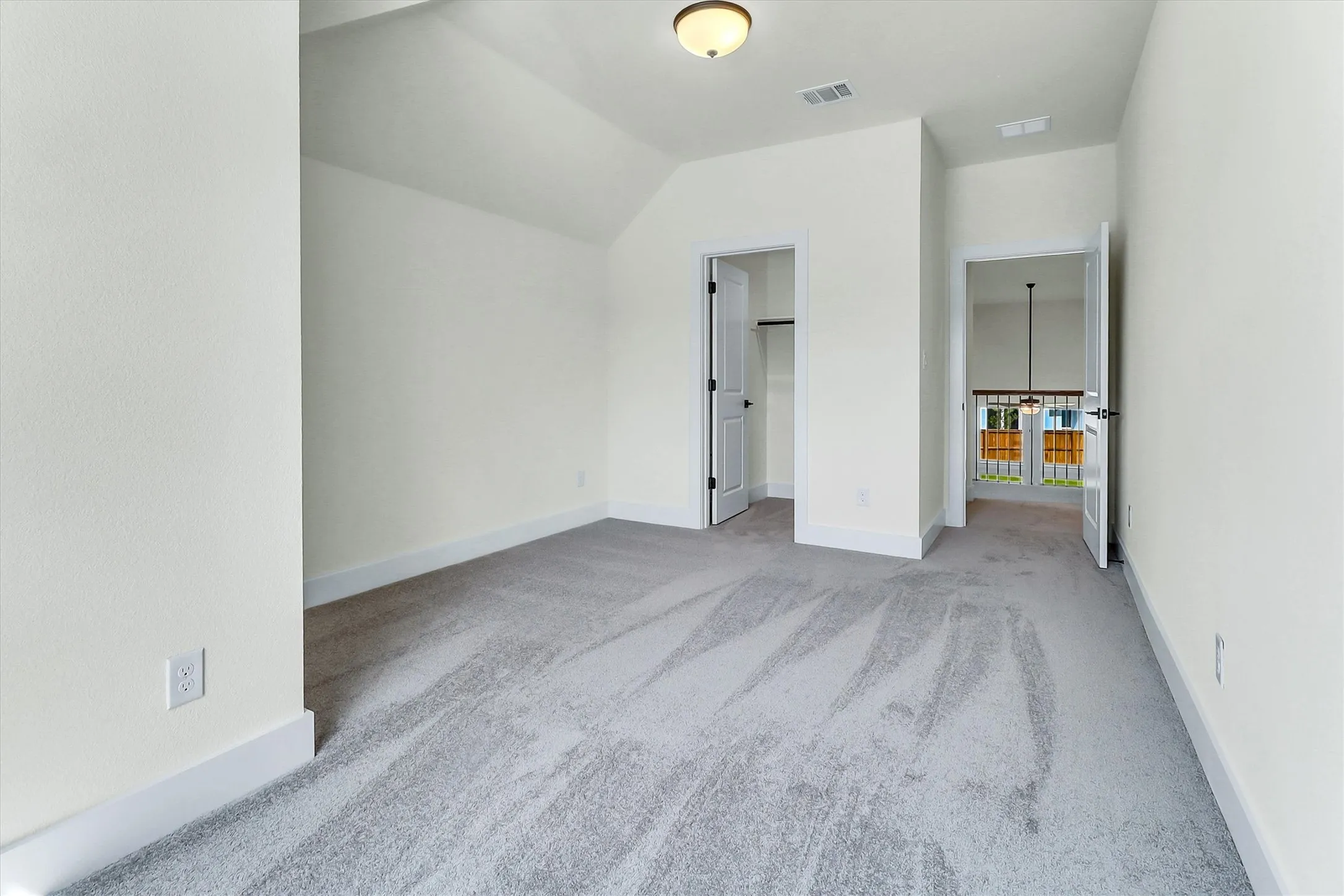 Carpeted room featuring a sloped ceiling, overhead lighting, and white trim