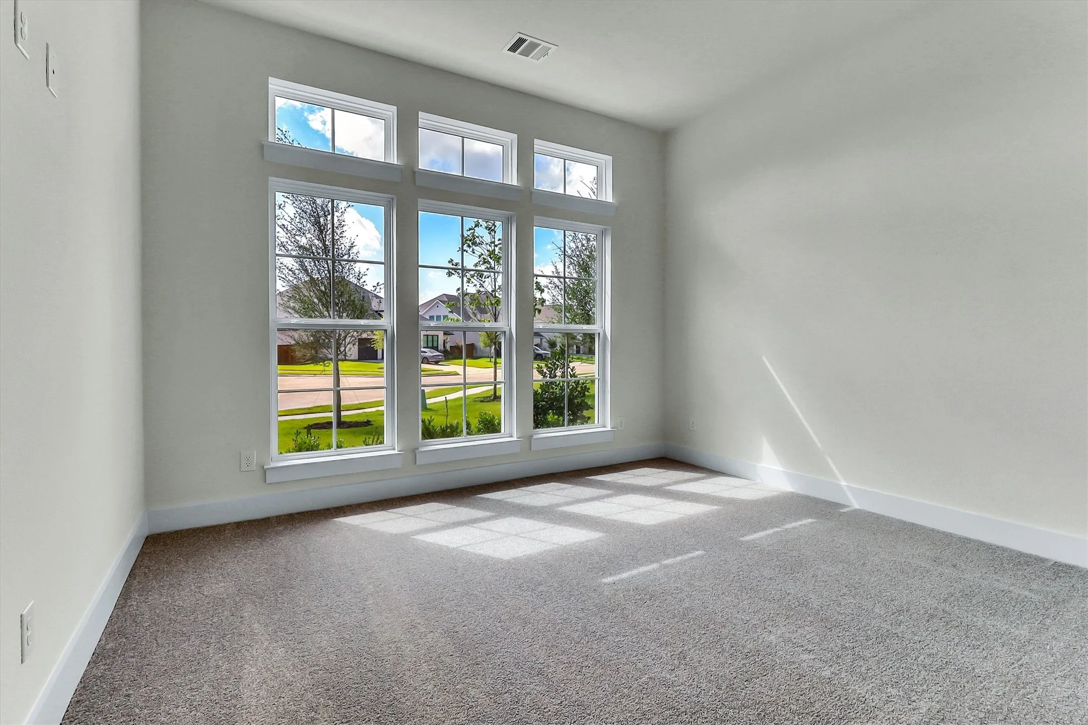 Expansive multi-pane windows with white trim, light-colored walls, and textured carpeting
