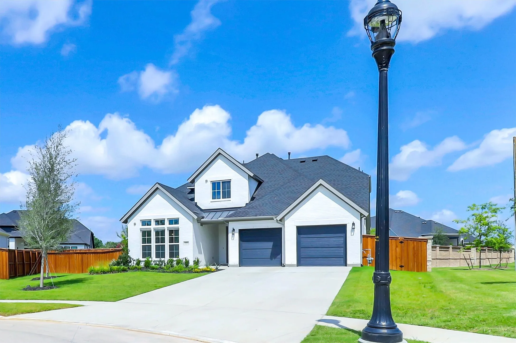 Modern farmhouse exterior with white siding and dark gray garage doors
