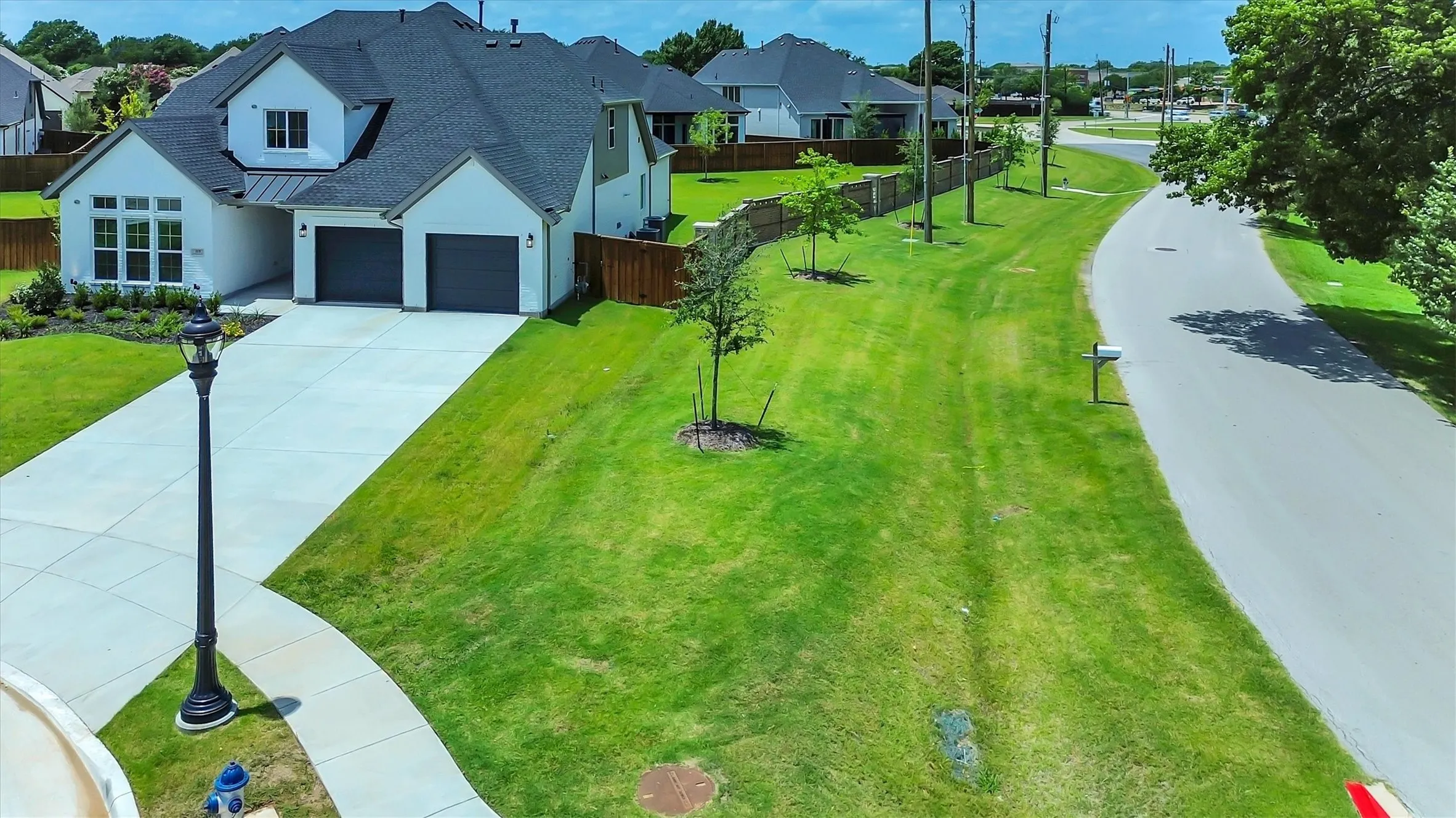 Contemporary architecture featuring a two-car garage, dormer window, extensive concrete driveway, and front landscaping