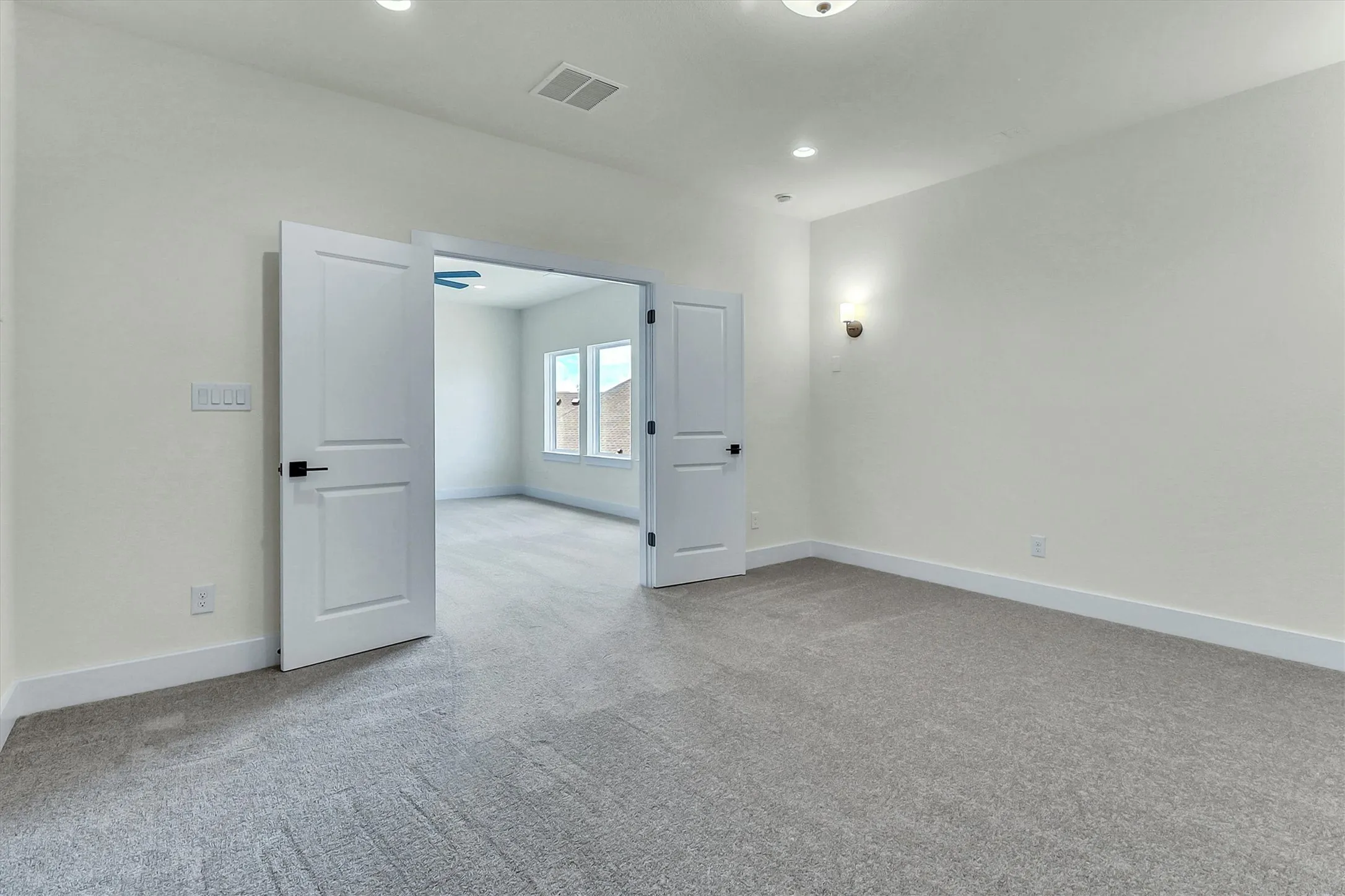 Neutral-toned carpeting, recessed lighting, and wall-mounted sconce