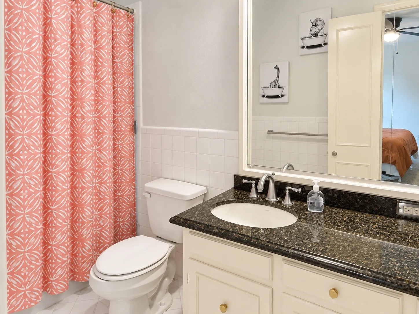White tile flooring, white tile wainscoting, built-in vanity with dark speckled countertop, undermount sink, and brushed nickel faucet