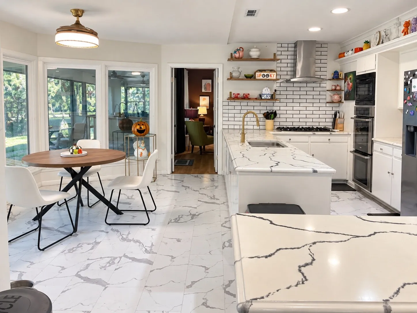 White kitchen cabinetry with integrated double ovens, white subway tile backsplash, and a stainless steel range hood