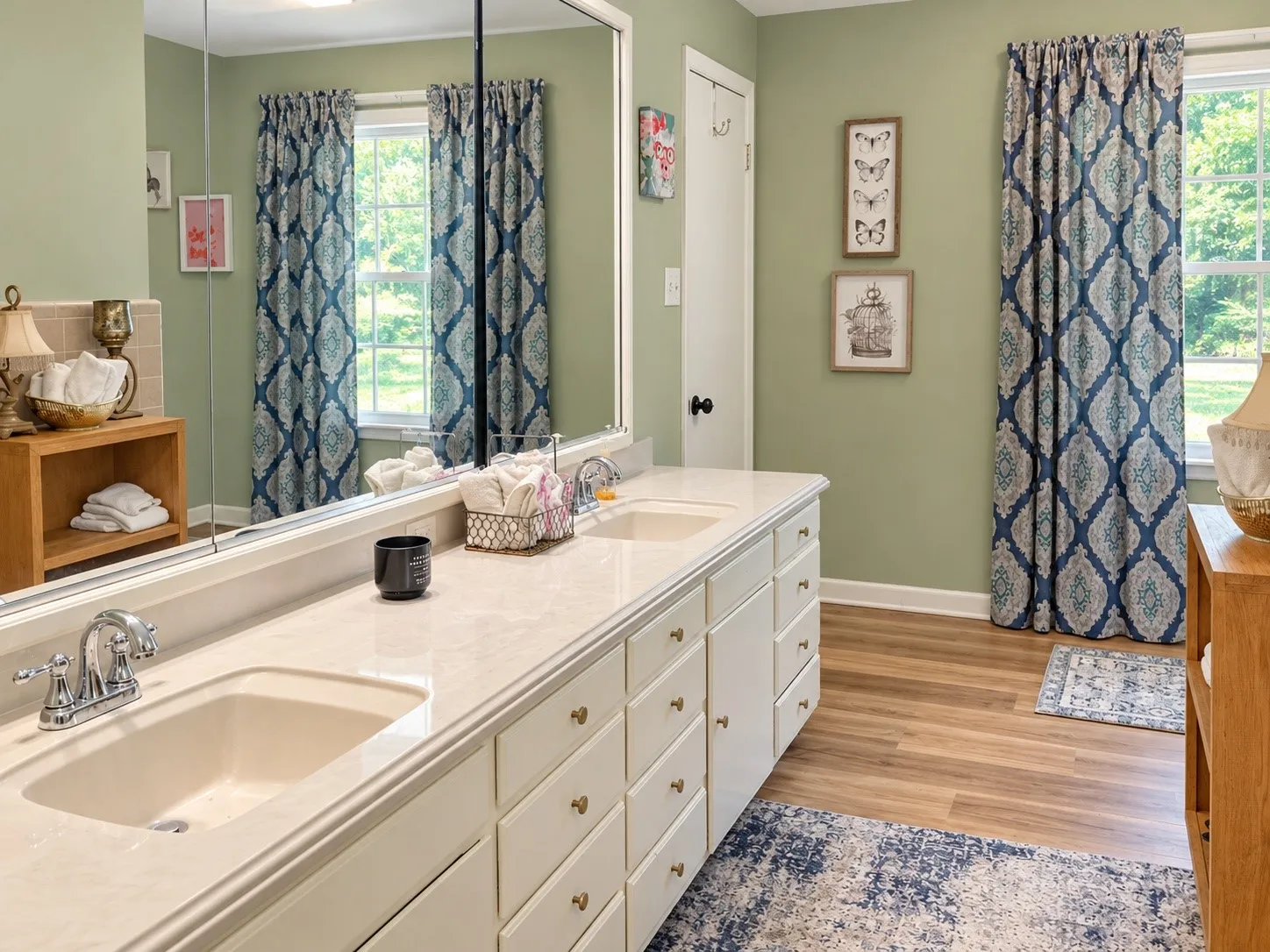 Dual vanity with integrated sinks, extensive counter space, white cabinetry, and wood-finish flooring