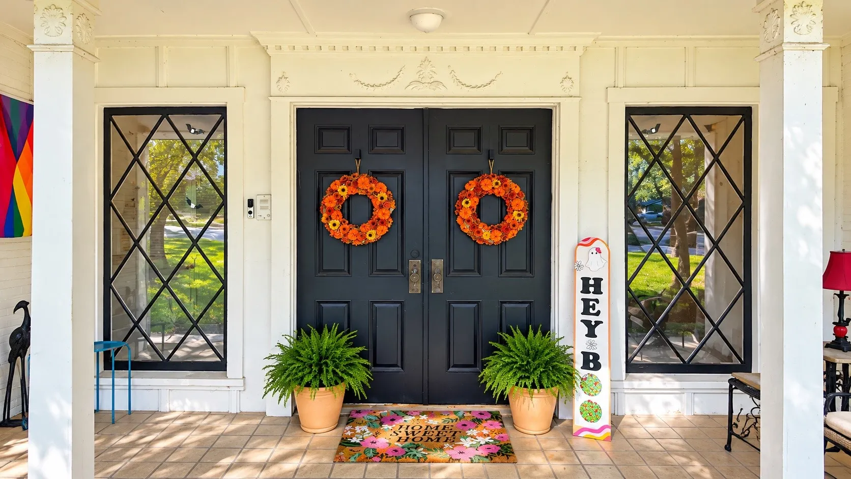 Classic double-door entry with diamond-pane sidelights, featuring a covered porch, white columns, and decorative trim