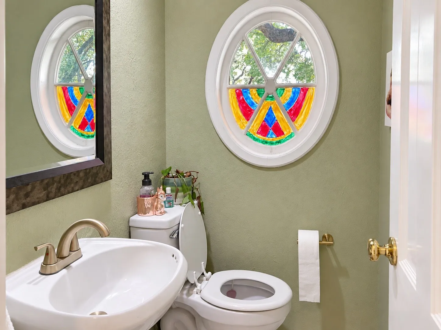 Pedestal sink with a brushed nickel faucet, oval window, and brass door hardware