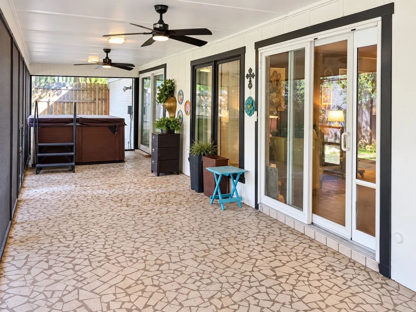 Screened-in patio with mosaic tile flooring, multiple ceiling fans, and sliding glass doors